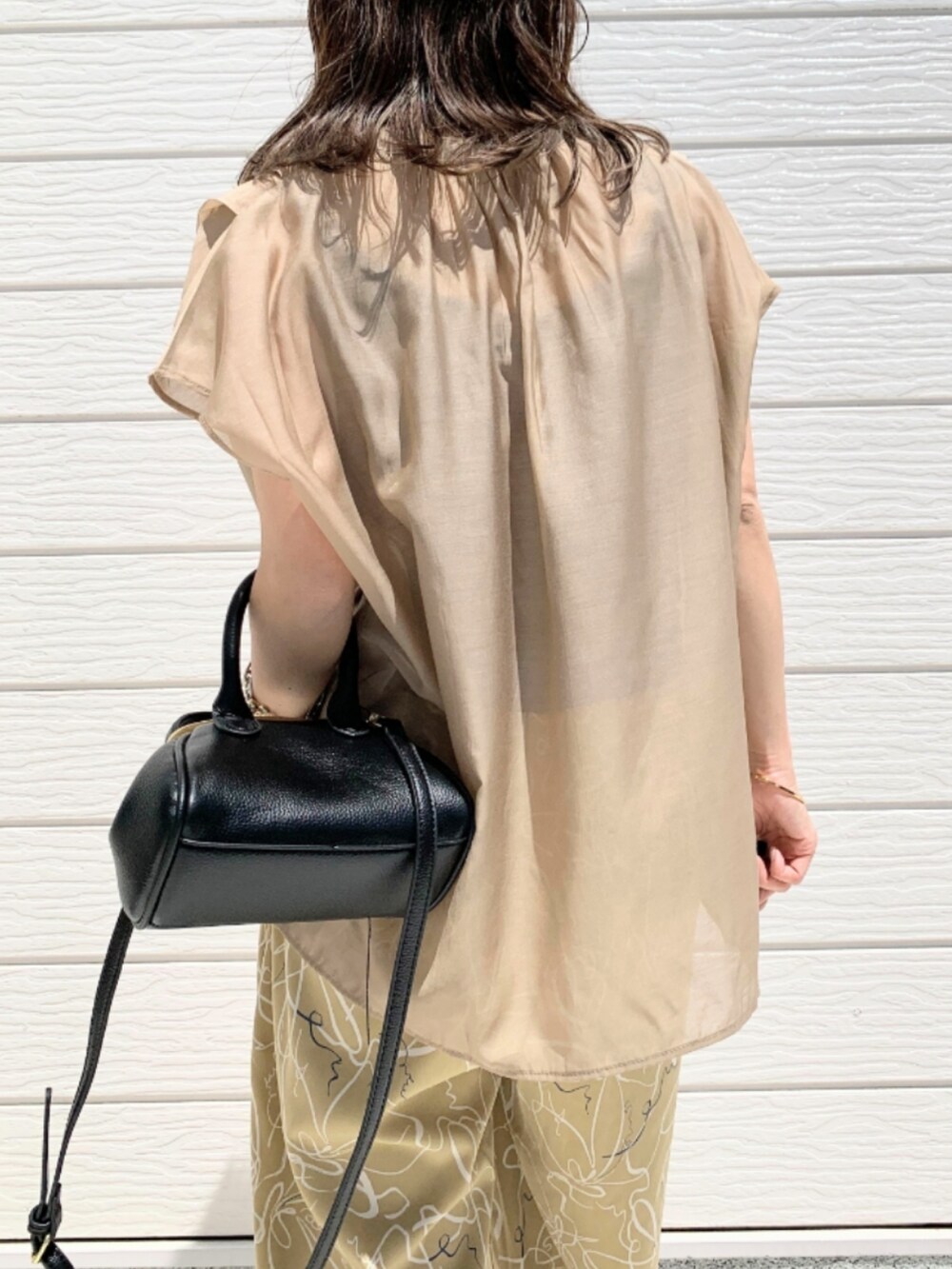 ブラウン系のサンダル、ベージュ系のその他パンツ、ブラック系のショルダーバッグを着用したレディースの春コーディネートの4枚目の写真