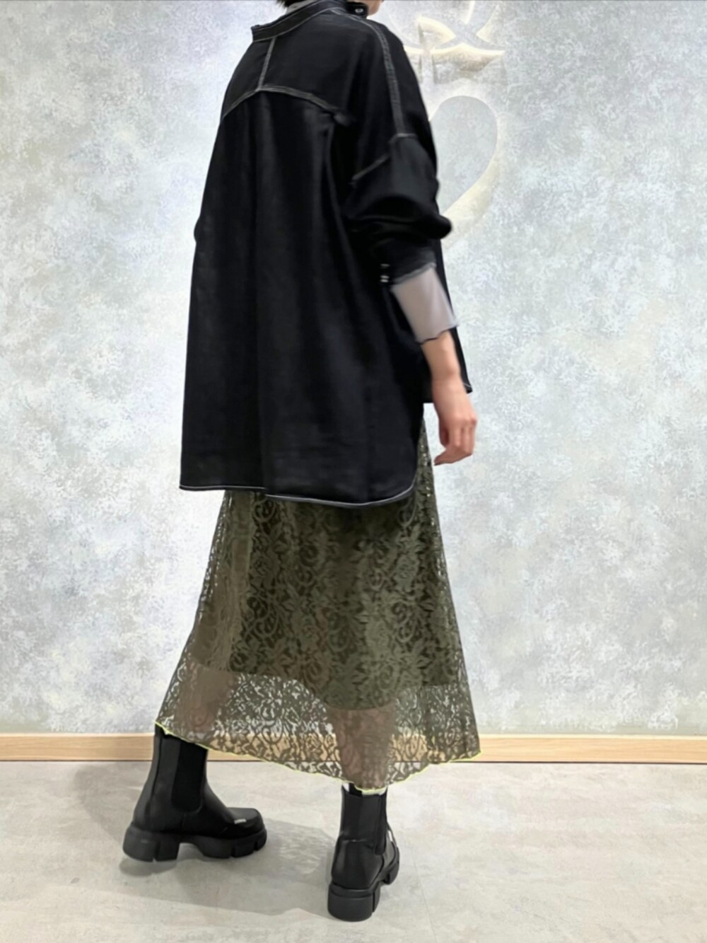 ブラック系のブーツ、グリーン系のスカート、ベージュ系のトートバッグを着用したレディースの秋コーディネートの3枚目の写真