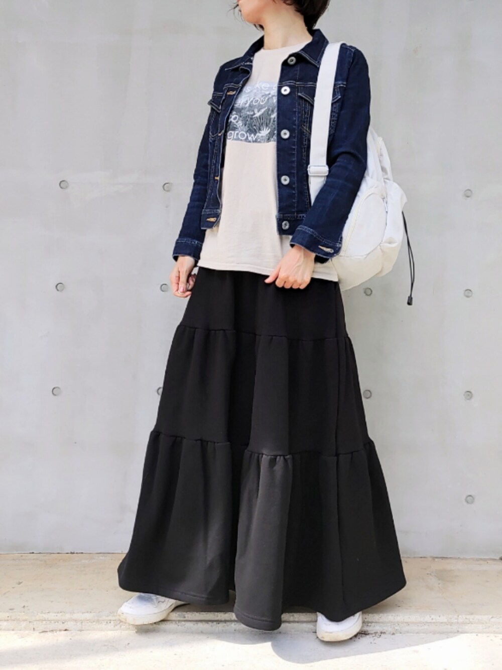 ブラック系のスカート、ホワイト系のバックパック/リュック、ベージュ系のTシャツ/カットソーを着用したレディースの秋コーディネートの3枚目の写真