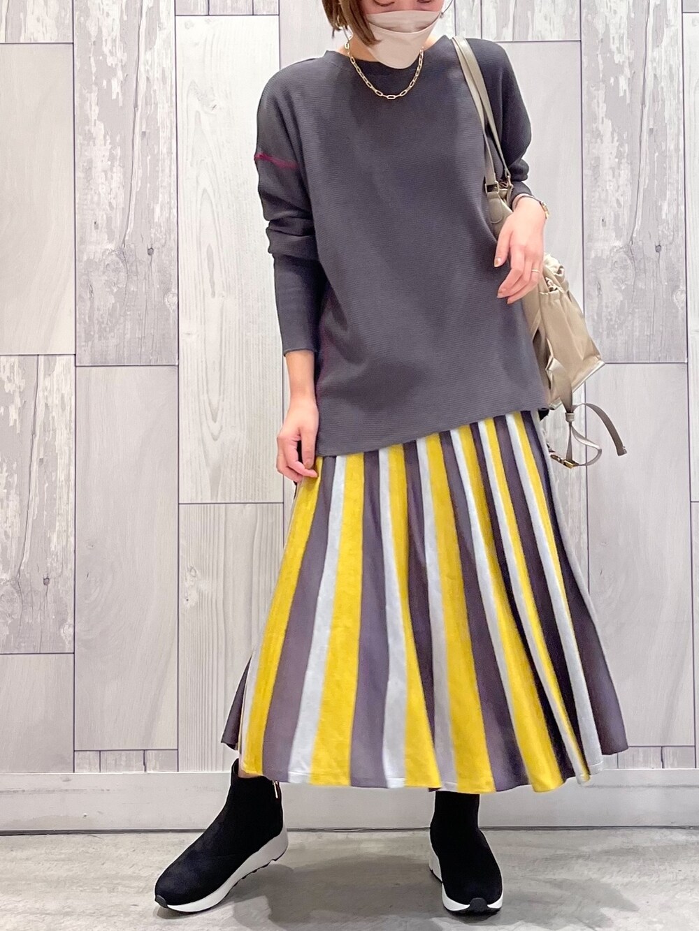 ベージュ系のバックパック/リュック、イエロー系のスカート、グレー系のTシャツ/カットソーを着用したレディースの秋コーディネートの2枚目の写真