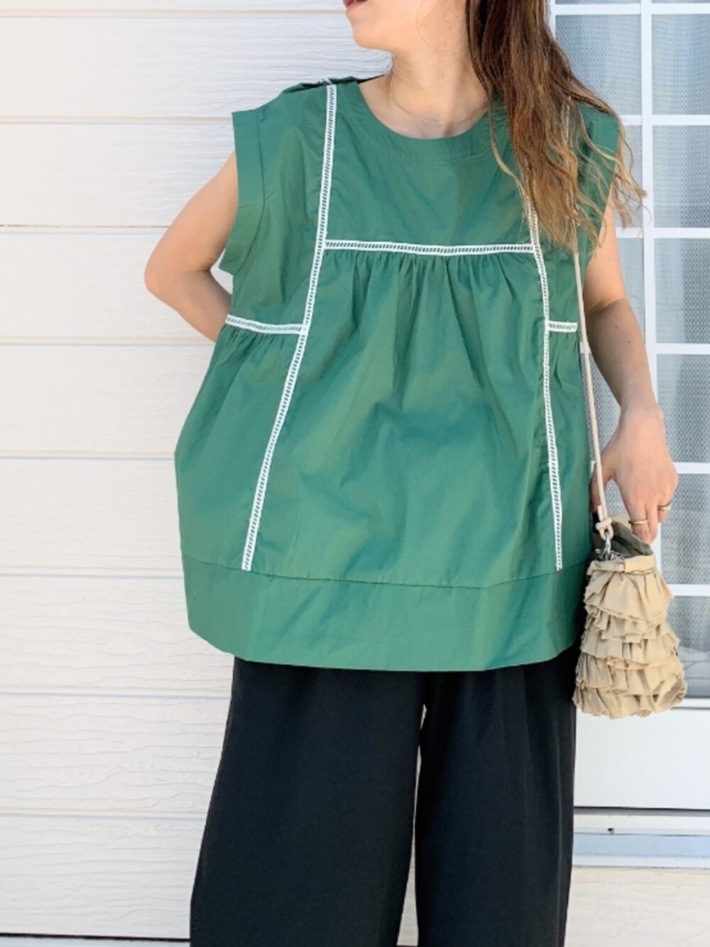 ブラック系のその他パンツ、グリーン系のシャツ/ブラウス、ベージュ系のクラッチバッグを着用したレディースの夏コーディネートの3枚目の写真