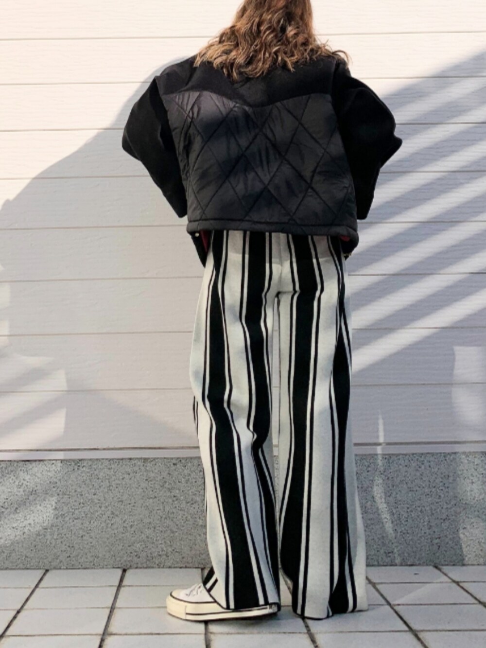 ブラック系のその他パンツ、ホワイト系のTシャツ/カットソー、ホワイト系のスニーカーを着用したレディースの冬コーディネートの3枚目の写真