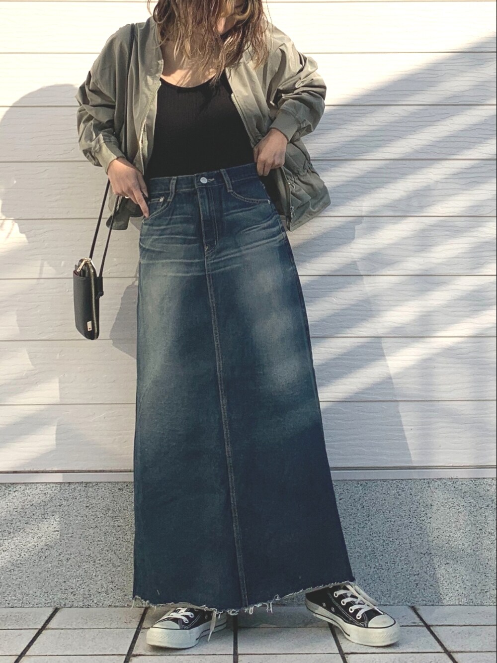 ブラック系のキャミソール、ブルー系のデニムスカート、ブラック系のスニーカーを着用したレディースの冬コーディネートの3枚目の写真