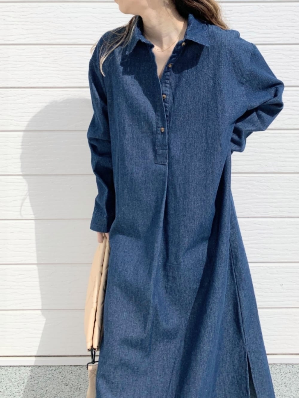 ブラック系のサンダル、ブルー系のシャツワンピース、ベージュ系のクラッチバッグを着用したレディースの春コーディネートの4枚目の写真