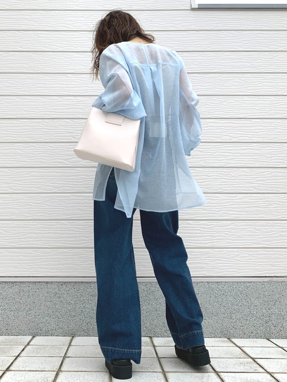 ブルー系のデニムパンツ、ブラック系のサンダル、ホワイト系のハンドバッグを着用したレディースの春コーディネートの4枚目の写真