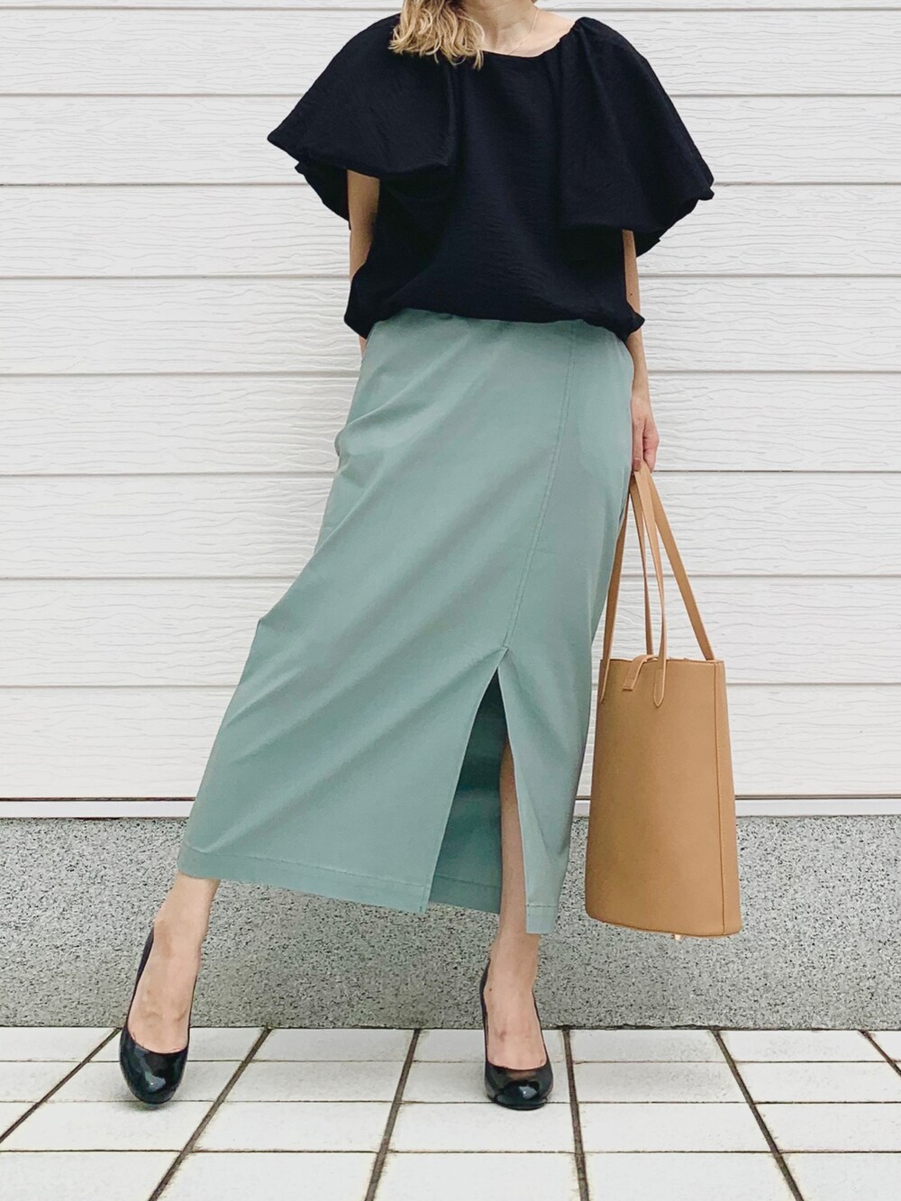 グリーン系のスカート、ベージュ系のトートバッグ、ブラック系のシャツ/ブラウスを着用したレディースの春コーディネートの2枚目の写真