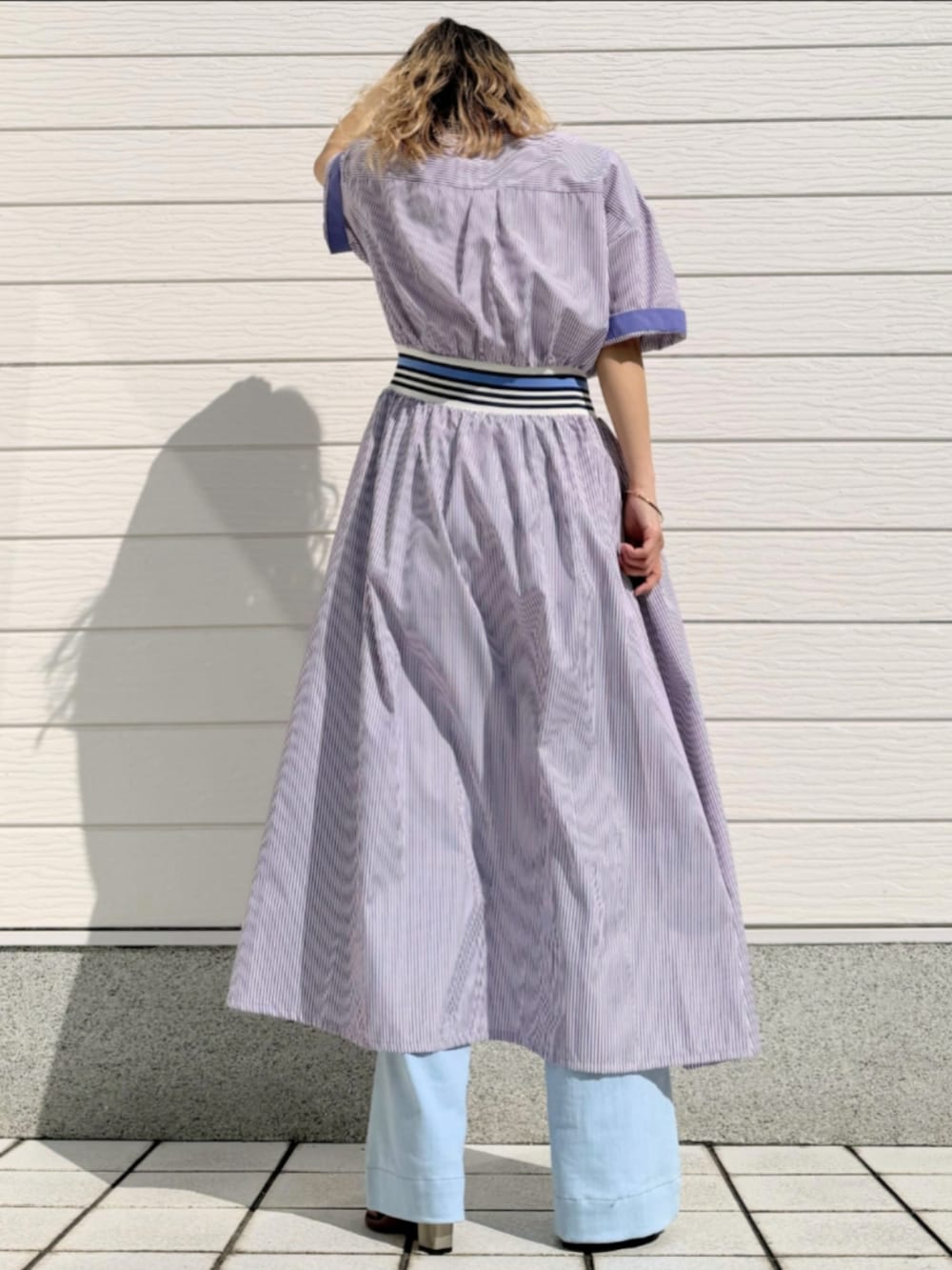 ブルー系のデニムパンツ、シルバー系のトートバッグ、パープル系のワンピースを着用したレディースの春コーディネートの3枚目の写真