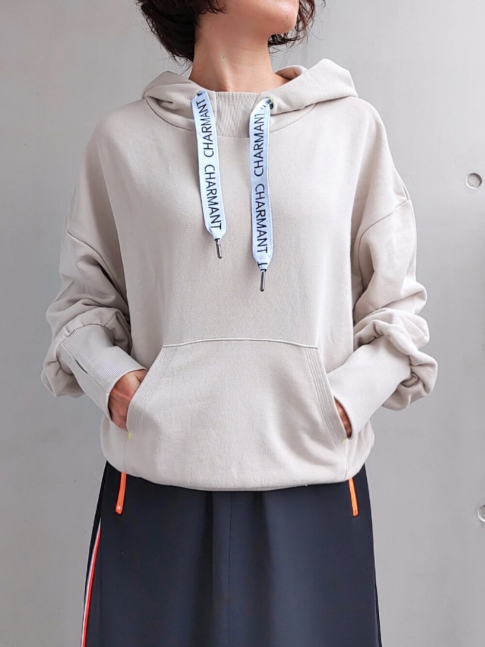 ブラック系のスカート、ベージュ系のパーカー、ホワイト系のスニーカーを着用したレディースの秋コーディネートの4枚目の写真