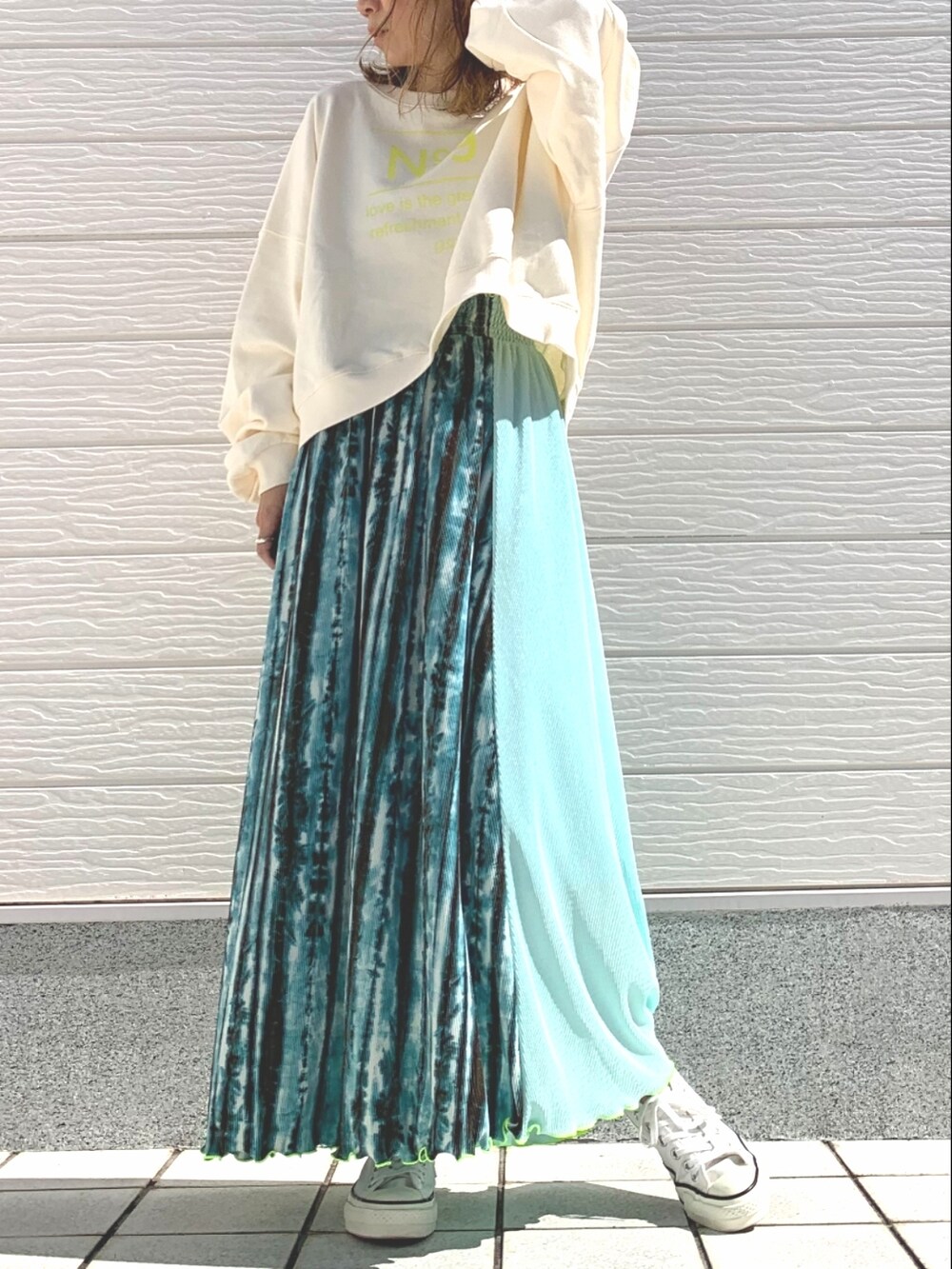 グリーン系のスカート、ホワイト系のスニーカー、ホワイト系のスウェットを着用したレディースの春コーディネートの2枚目の写真