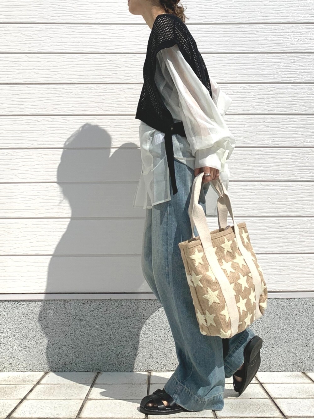 ブルー系のデニムパンツ、ブラック系のサンダル、ホワイト系のシャツ/ブラウスを着用したレディースの春コーディネートの3枚目の写真