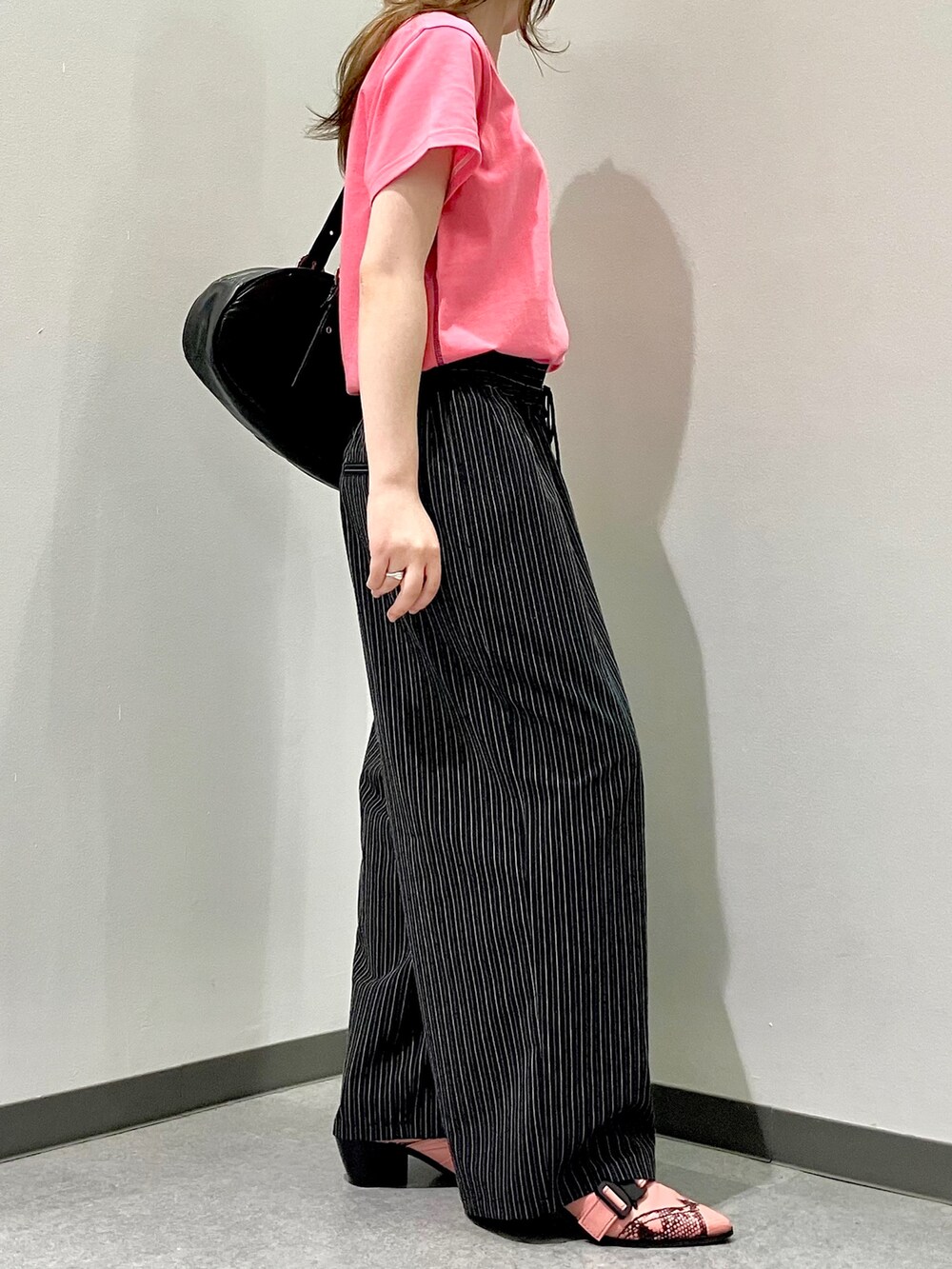 ピンク系のTシャツ/カットソー、ブラック系のスラックス、ブラック系のボストンバッグを着用したレディースの夏コーディネートの2枚目の写真