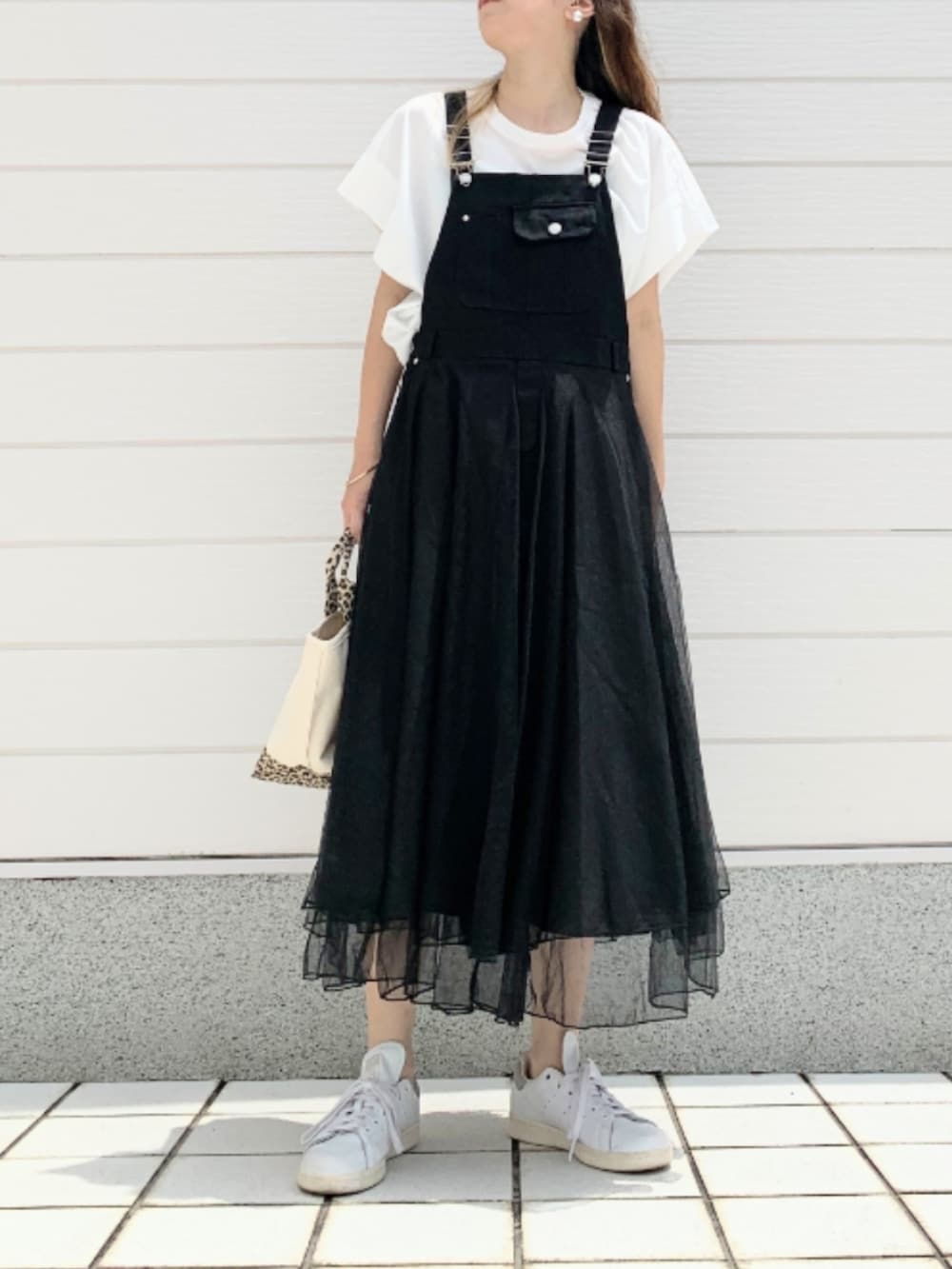 ホワイト系のスニーカー、ブラック系のジャンパースカート、ホワイト系のTシャツ/カットソーを着用したレディースの夏コーディネートの2枚目の写真