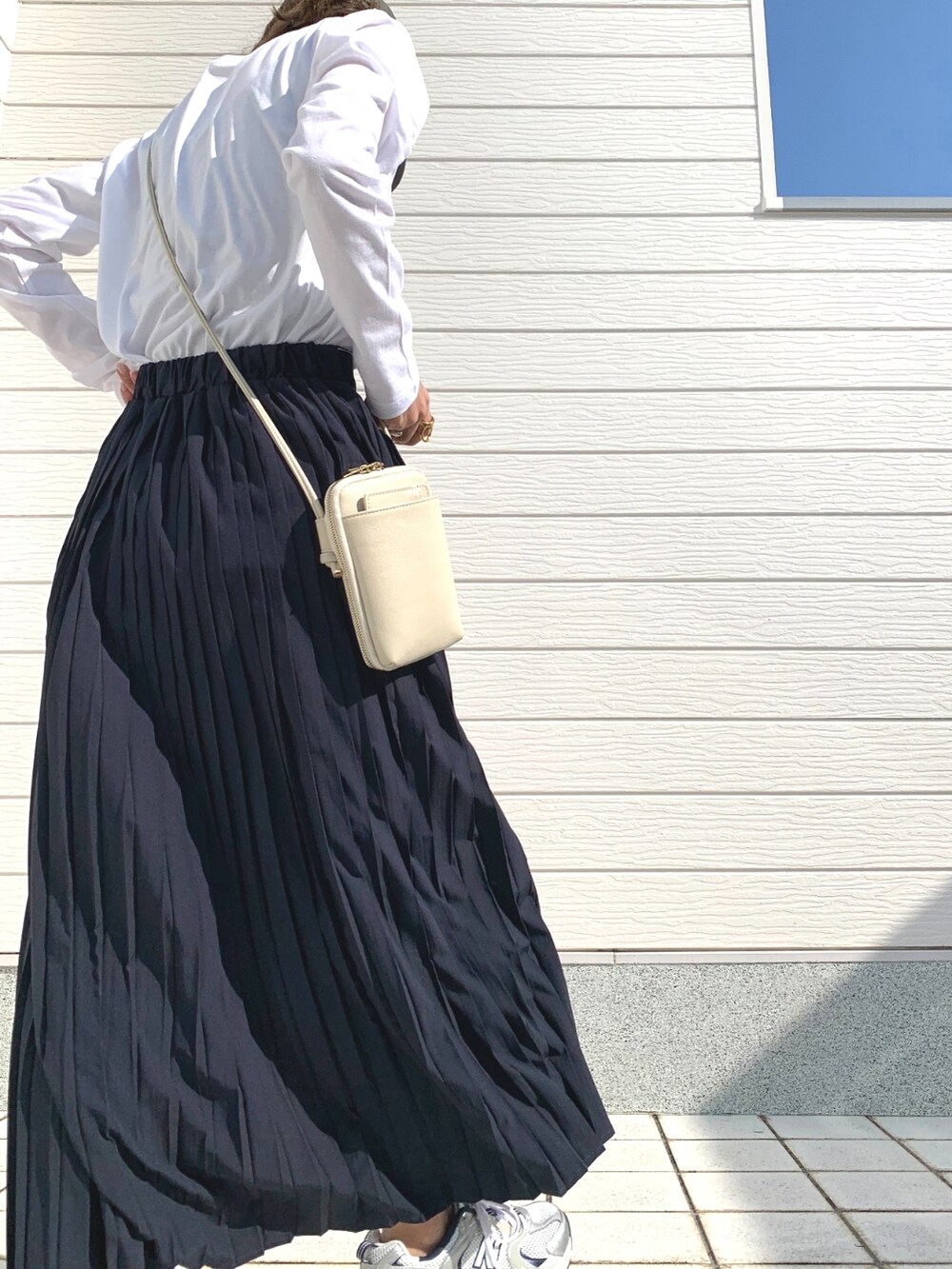 シルバー系のスニーカー、ブルー系のデニムスカート、ホワイト系のTシャツ/カットソーを着用したレディースの冬コーディネートの2枚目の写真