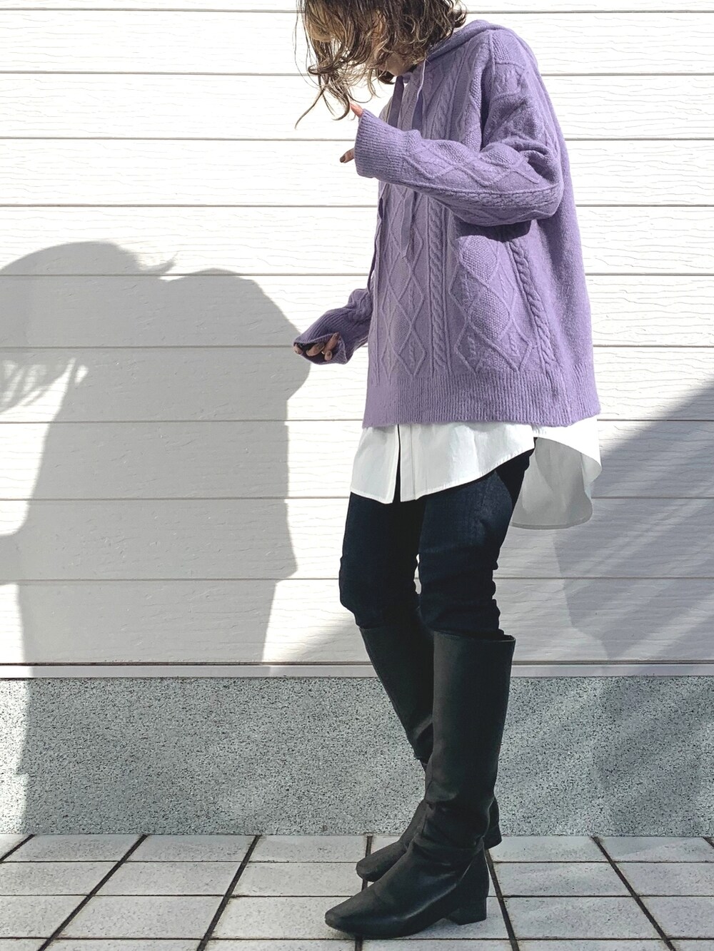 ブラック系のブーツ、ブルー系のデニムパンツ、ホワイト系のショルダーバッグを着用したレディースの秋コーディネートの2枚目の写真