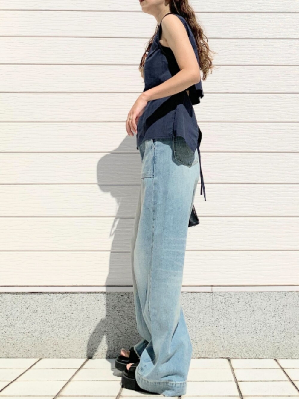ブルー系のデニムパンツ、ブラック系のサンダル、ブルー系のシャツ/ブラウスを着用したレディースの夏コーディネートの2枚目の写真