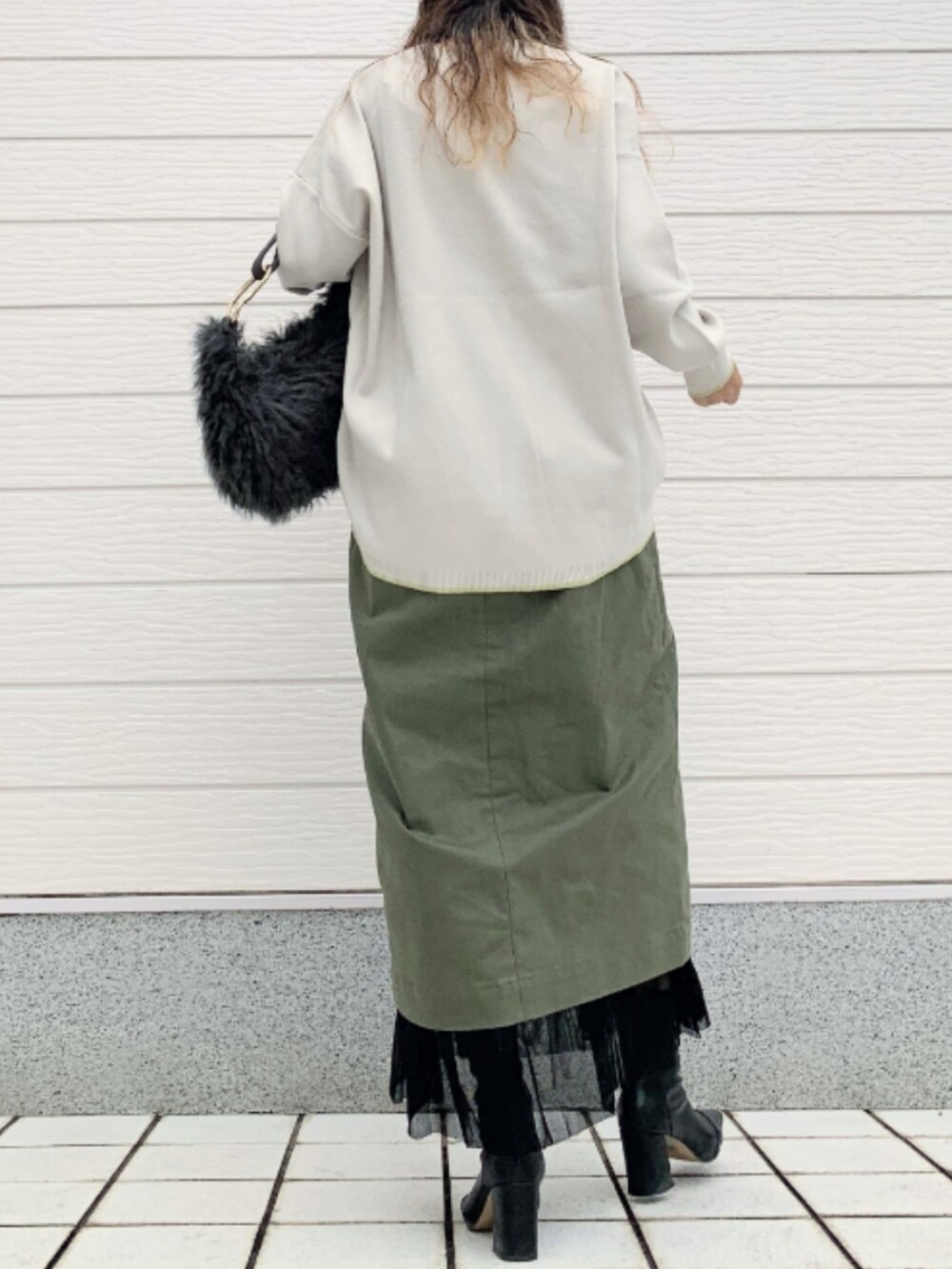 グリーン系のスカート、グレー系のハンドバッグ、グレー系のニット/セーターを着用したレディースの秋コーディネートの3枚目の写真