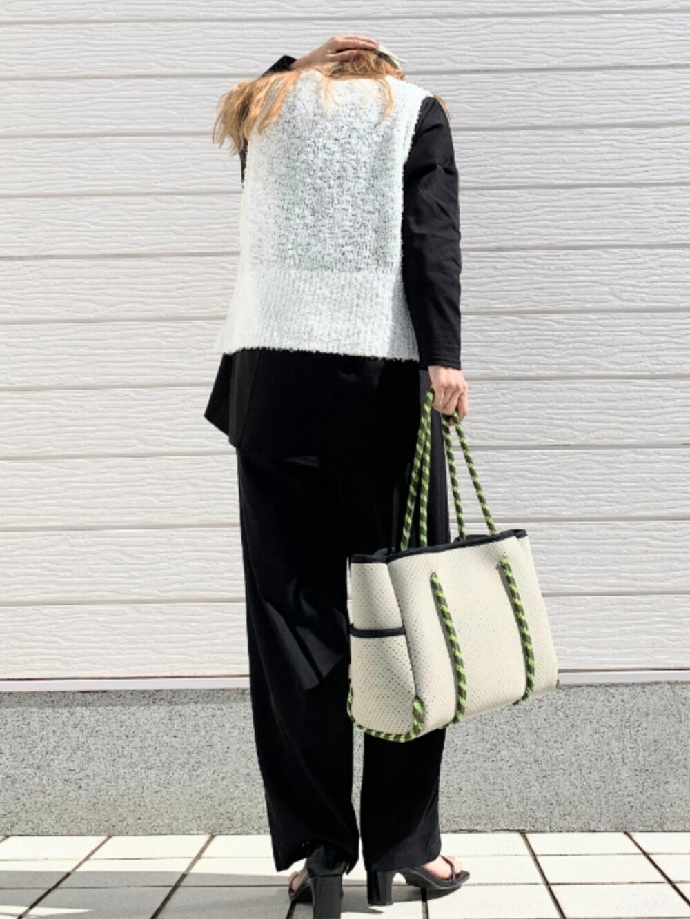 グレー系のトートバッグ、ブラック系のスラックス、ブラック系のTシャツ/カットソーを着用したレディースの冬コーディネートの3枚目の写真