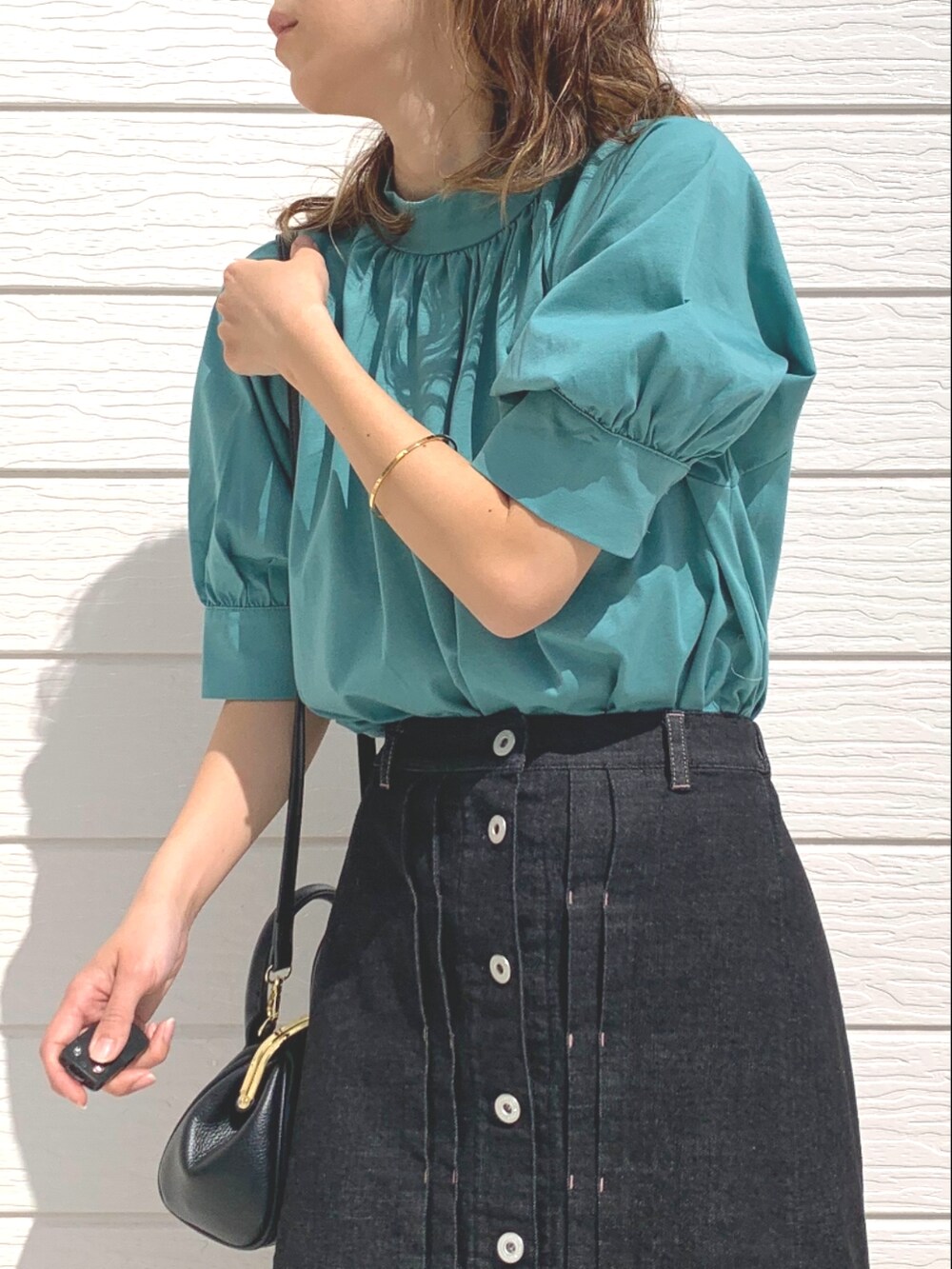 グリーン系のシャツ/ブラウス、ブラック系のデニムスカート、ブラック系のショルダーバッグを着用したレディースの春コーディネートの4枚目の写真