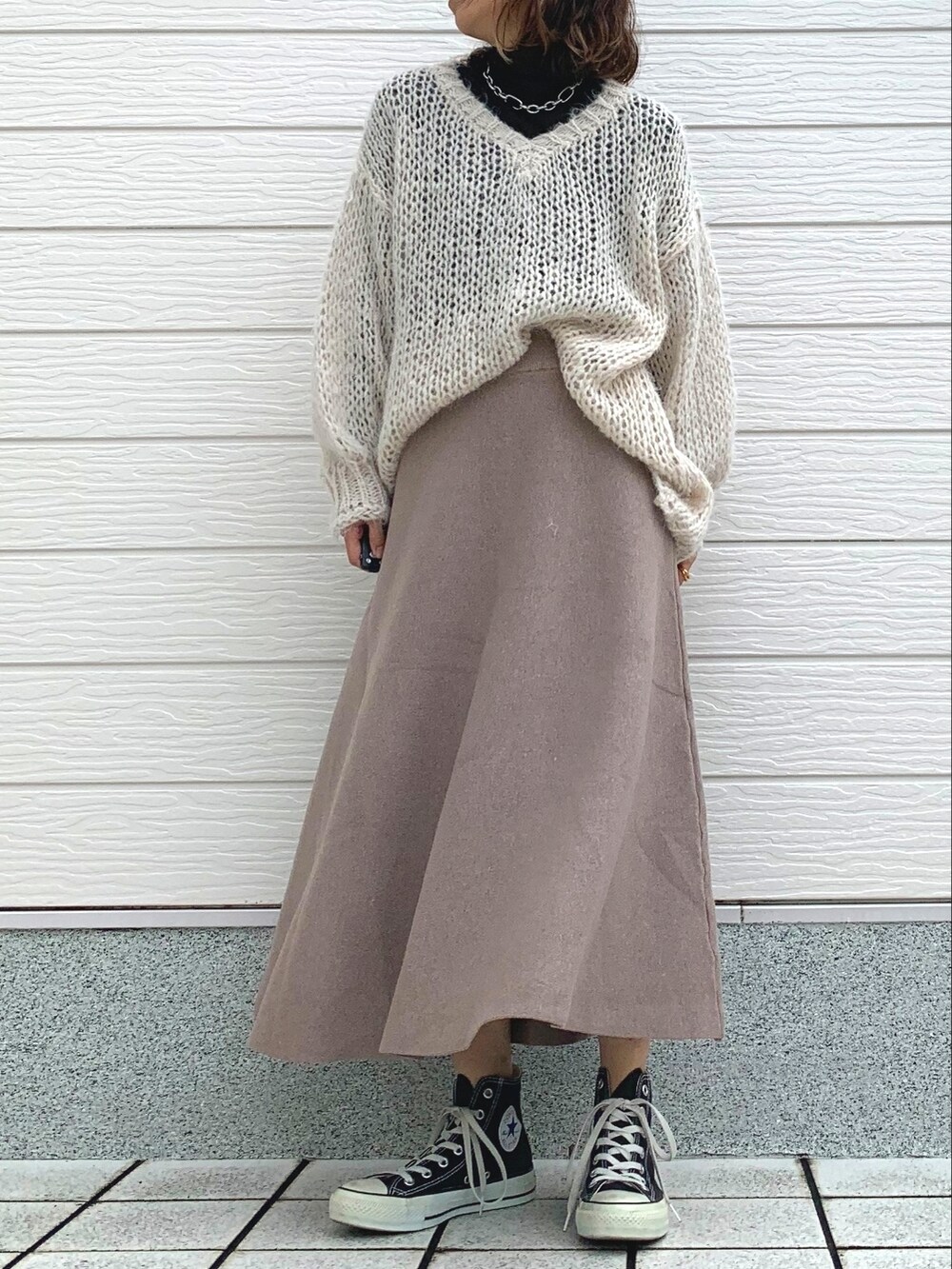 ホワイト系のニット/セーター、ブラック系のTシャツ/カットソー、ブラック系のスニーカーを着用したレディースの冬コーディネートの2枚目の写真