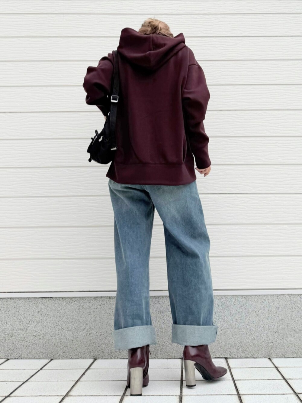 ブルー系のデニムパンツ、ブラウン系のブーツ、ブラック系のショルダーバッグを着用したレディースの秋コーディネートの3枚目の写真