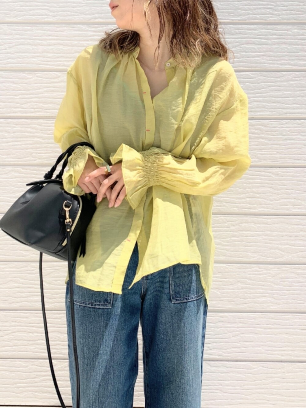 ブルー系のデニムパンツ、ブラウン系のサンダル、ブラック系のハンドバッグを着用したレディースの春コーディネートの3枚目の写真