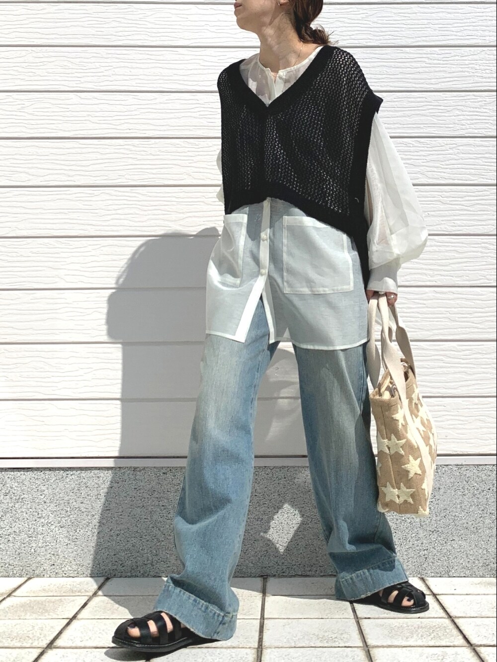 ブルー系のデニムパンツ、ブラック系のサンダル、ホワイト系のシャツ/ブラウスを着用したレディースの春コーディネートの2枚目の写真