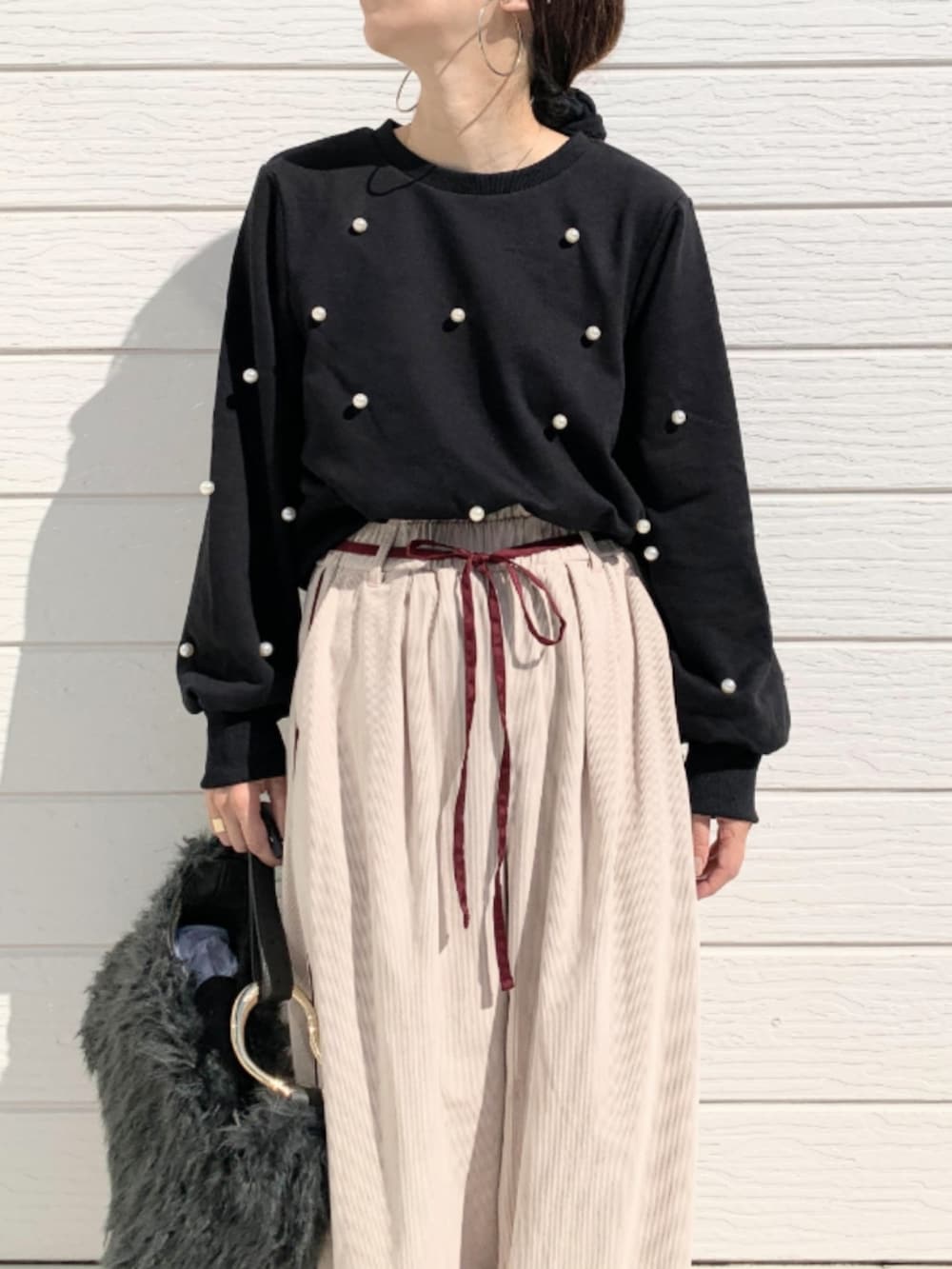 グレー系のハンドバッグ、ブラック系のスウェット、ベージュ系のその他パンツを着用したレディースの秋コーディネートの4枚目の写真