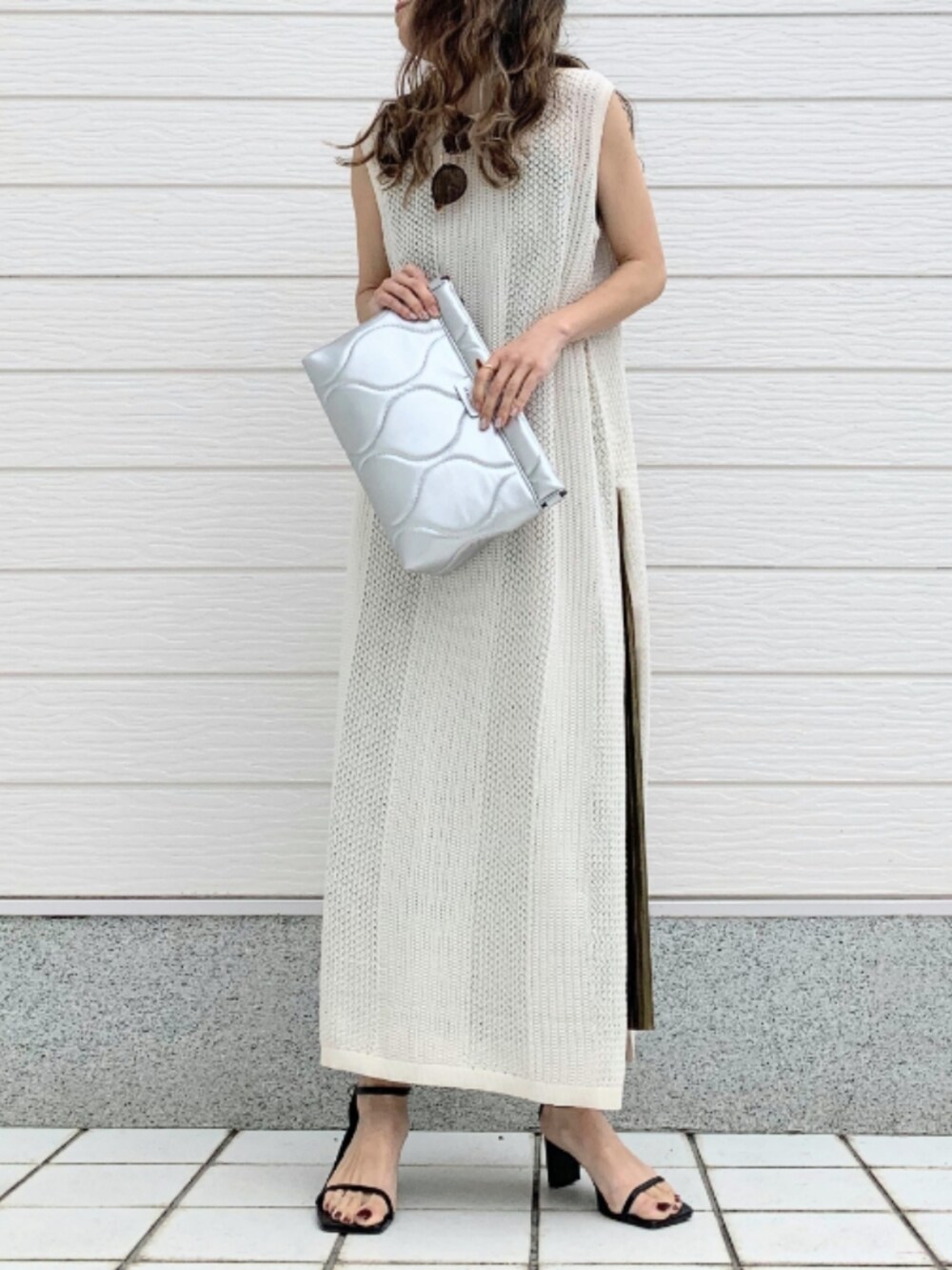 シルバー系のクラッチバッグ、ゴールド系のスカート、ホワイト系のワンピースを着用したレディースの春コーディネートの2枚目の写真