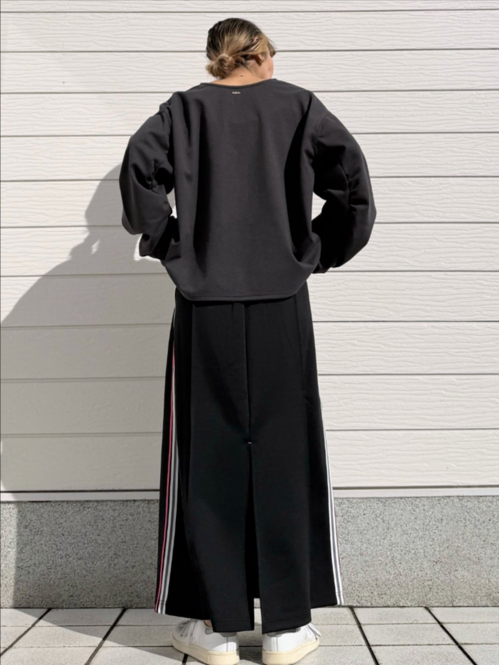 ブラック系のスカート、グレー系のTシャツ/カットソー、ホワイト系のスニーカーを着用したレディースの春コーディネートの3枚目の写真