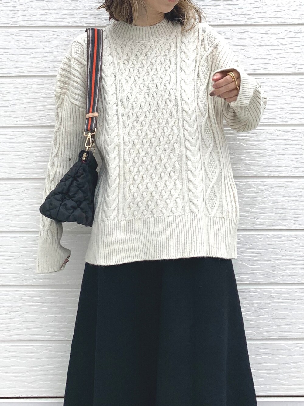 ブラック系のショルダーバッグ、ブラック系のスニーカー、ホワイト系のニット/セーターを着用したレディースの冬コーディネートの5枚目の写真