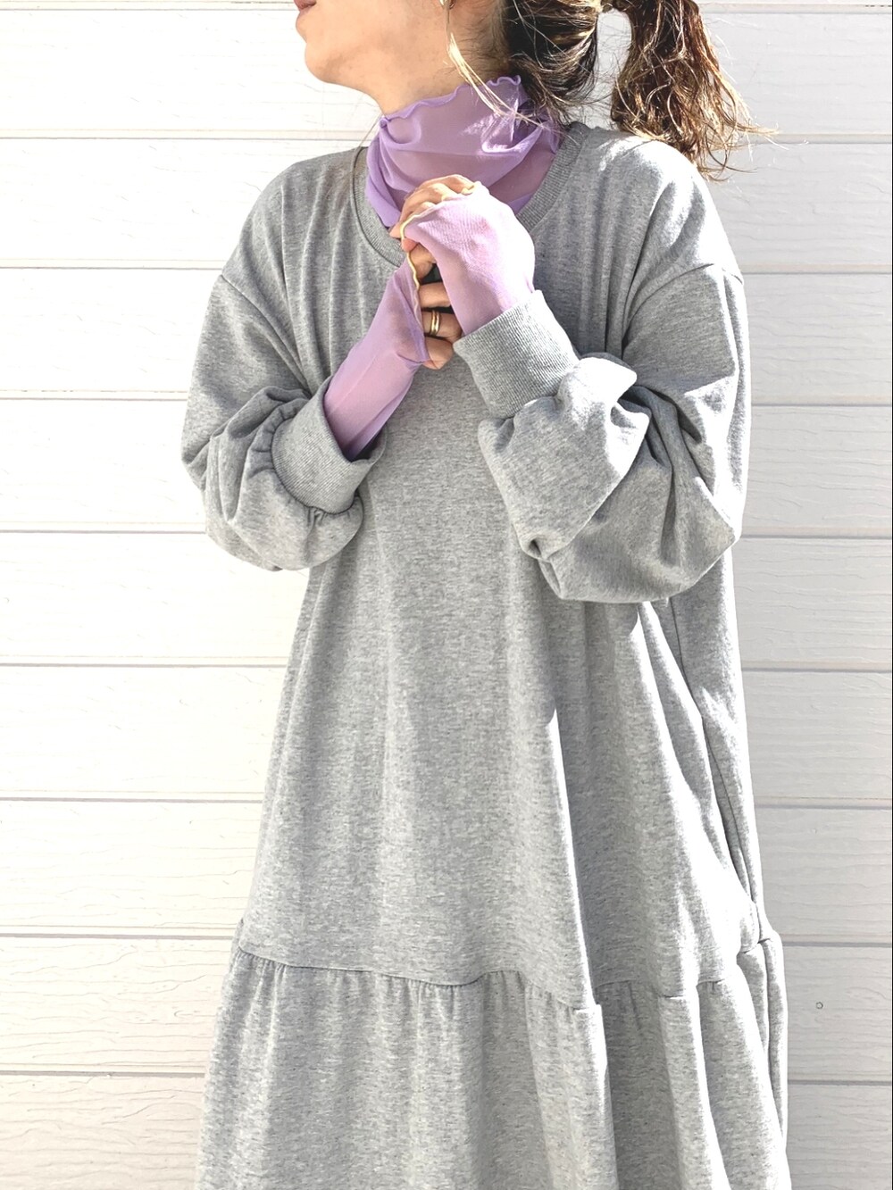 グレー系のワンピース、パープル系のTシャツ/カットソー、シルバー系のスニーカーを着用したレディースの冬コーディネートの2枚目の写真