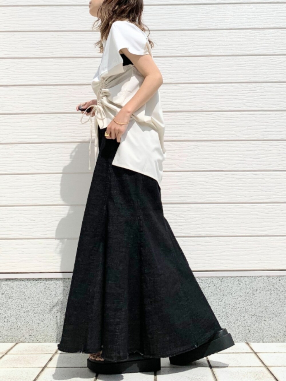 ブラック系のデニムスカート、ブラック系のサンダル、イエロー系のショルダーバッグを着用したレディースの春コーディネートの2枚目の写真