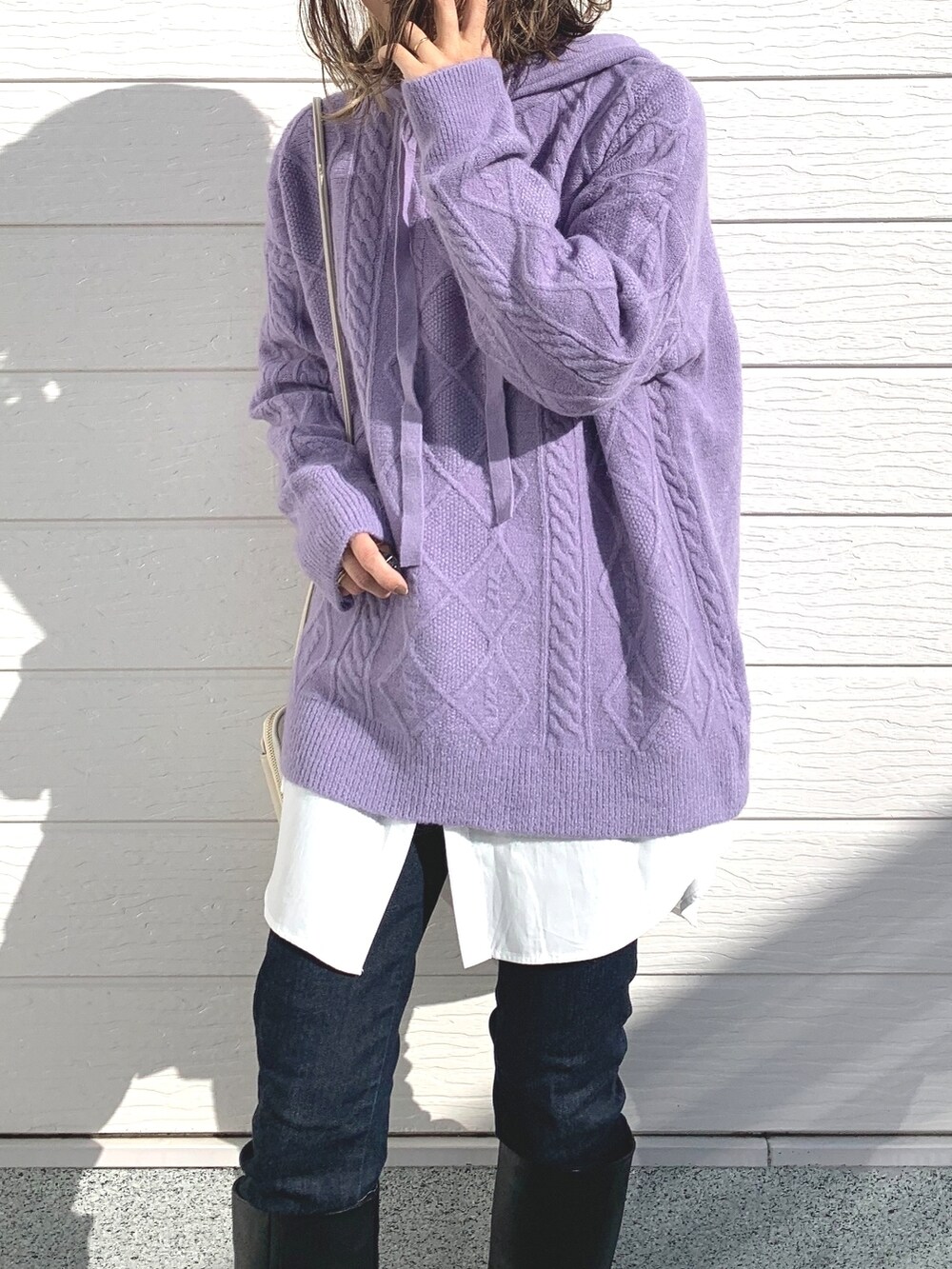 ブラック系のブーツ、ブルー系のデニムパンツ、ホワイト系のショルダーバッグを着用したレディースの秋コーディネートの4枚目の写真