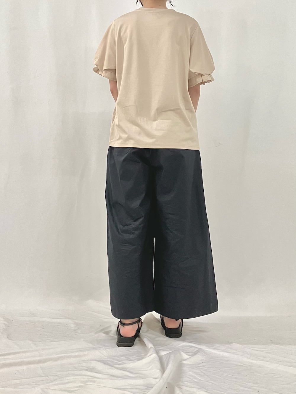 シルバー系のかごバッグ、ブラウン系のサンダル、ブルー系のスラックスを着用したレディースの夏コーディネートの3枚目の写真