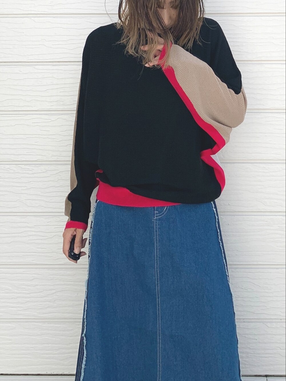 ブルー系のデニムスカート、ブラック系のスニーカー、ブラック系のニット/セーターを着用したレディースの夏コーディネートの3枚目の写真