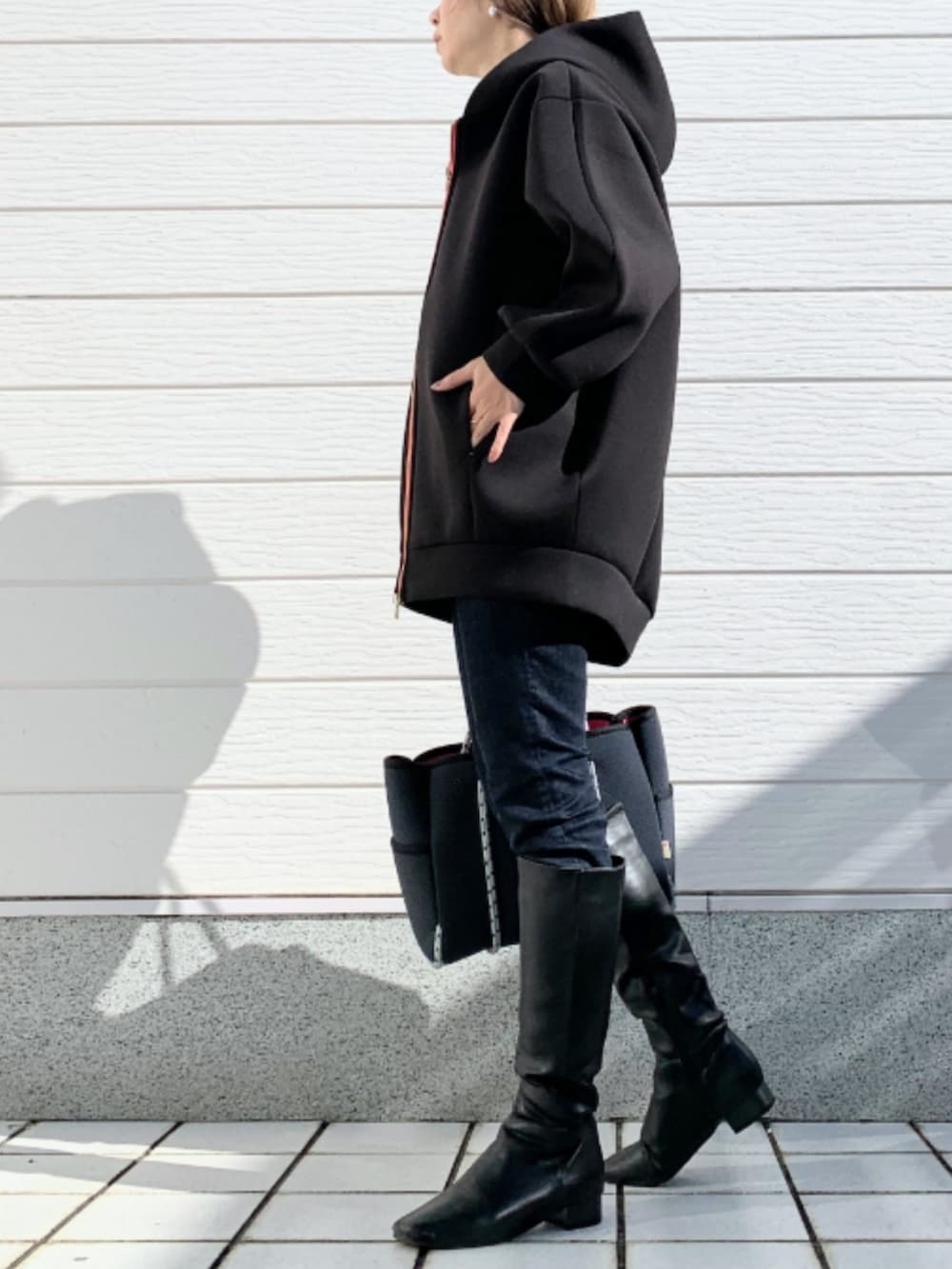 ブラック系のブーツ、ブルー系のデニムパンツ、ブルー系のトートバッグを着用したレディースの秋コーディネートの2枚目の写真