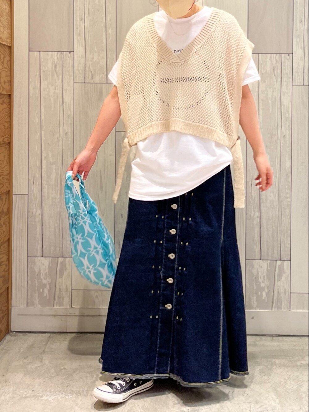 ブルー系のデニムスカート、ベージュ系のベスト、ホワイト系のTシャツ/カットソーを着用したレディースの春コーディネートの2枚目の写真