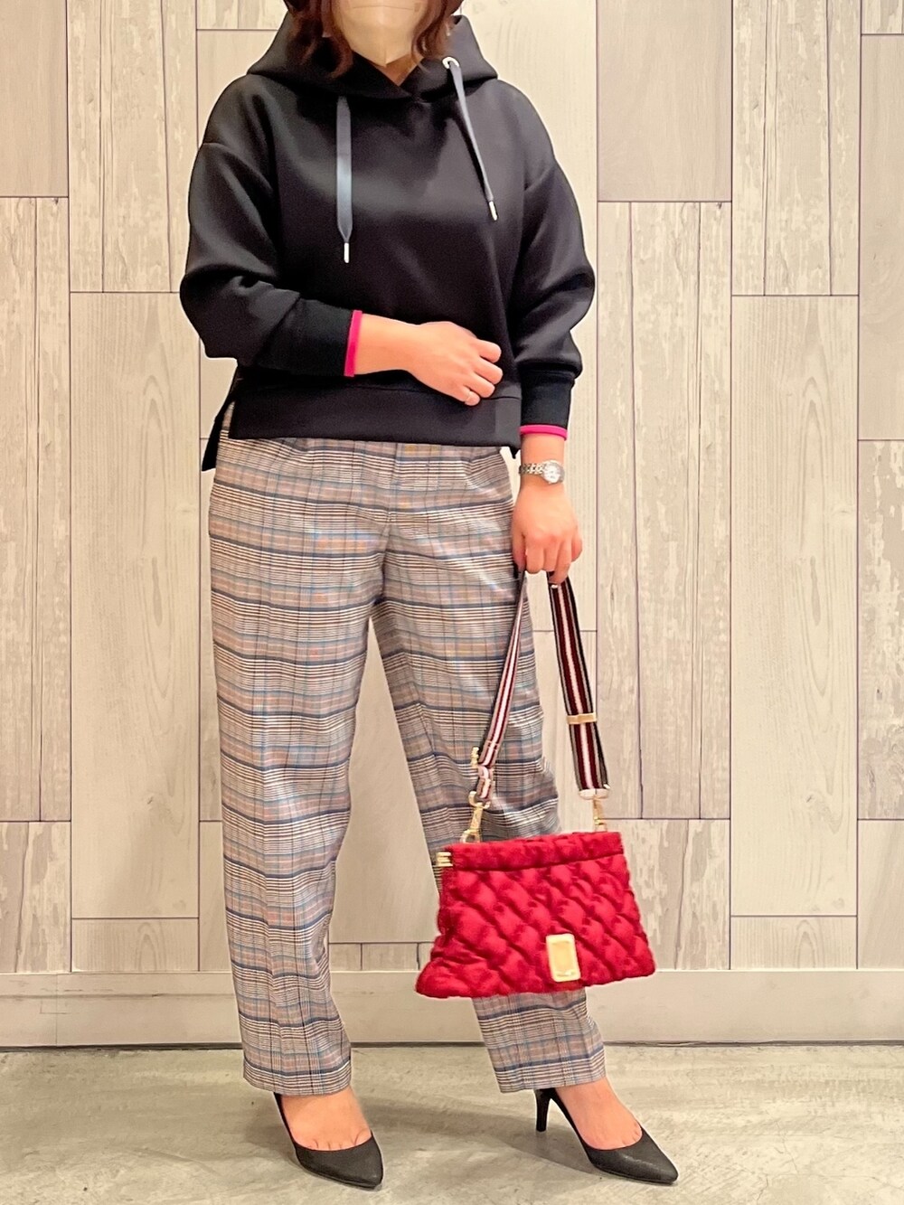 レッド系のショルダーバッグ、ブラック系のパーカー、ブラウン系のその他パンツを着用したレディースの秋コーディネートの2枚目の写真
