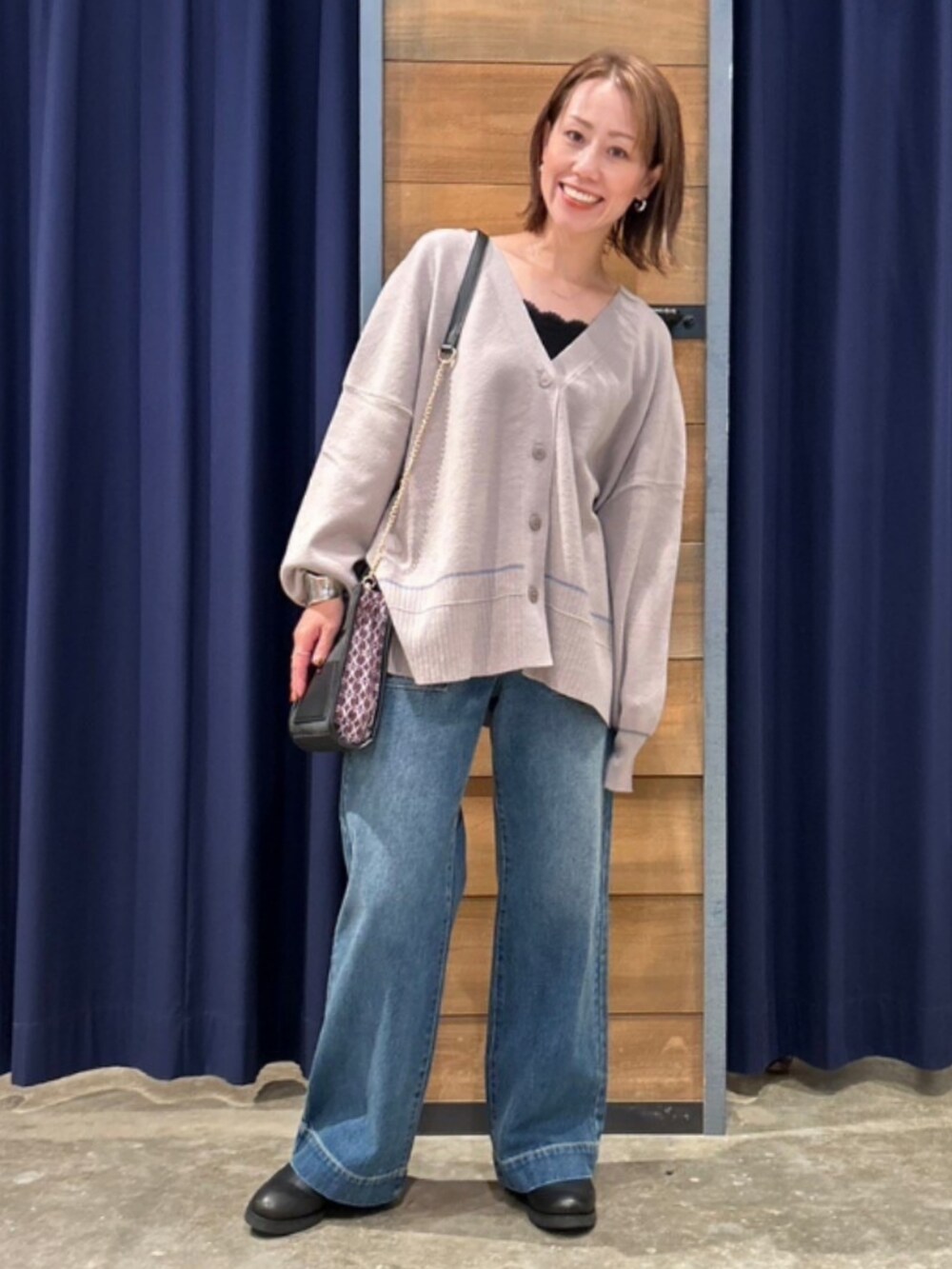 ブルー系のデニムパンツ、グレー系のカーディガン/ボレロ、ブラウン系のショルダーバッグを着用したレディースの秋コーディネートの2枚目の写真