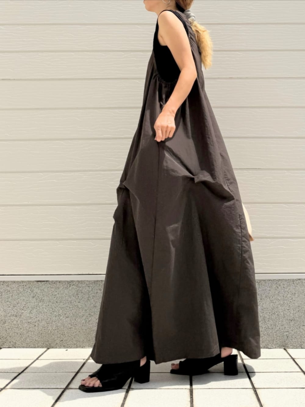 ブラック系のサンダル、ホワイト系のハンドバッグ、グレー系のワンピースを着用したレディースの夏コーディネートの2枚目の写真