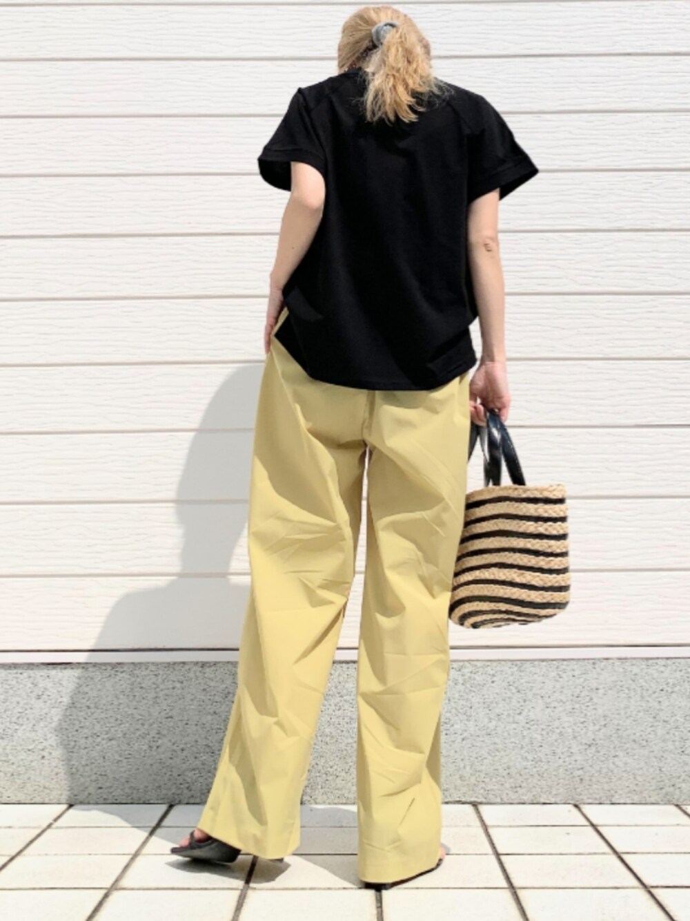 ブラック系のかごバッグ、イエロー系のその他パンツ、ブラック系のTシャツ/カットソーを着用したレディースの春コーディネートの3枚目の写真