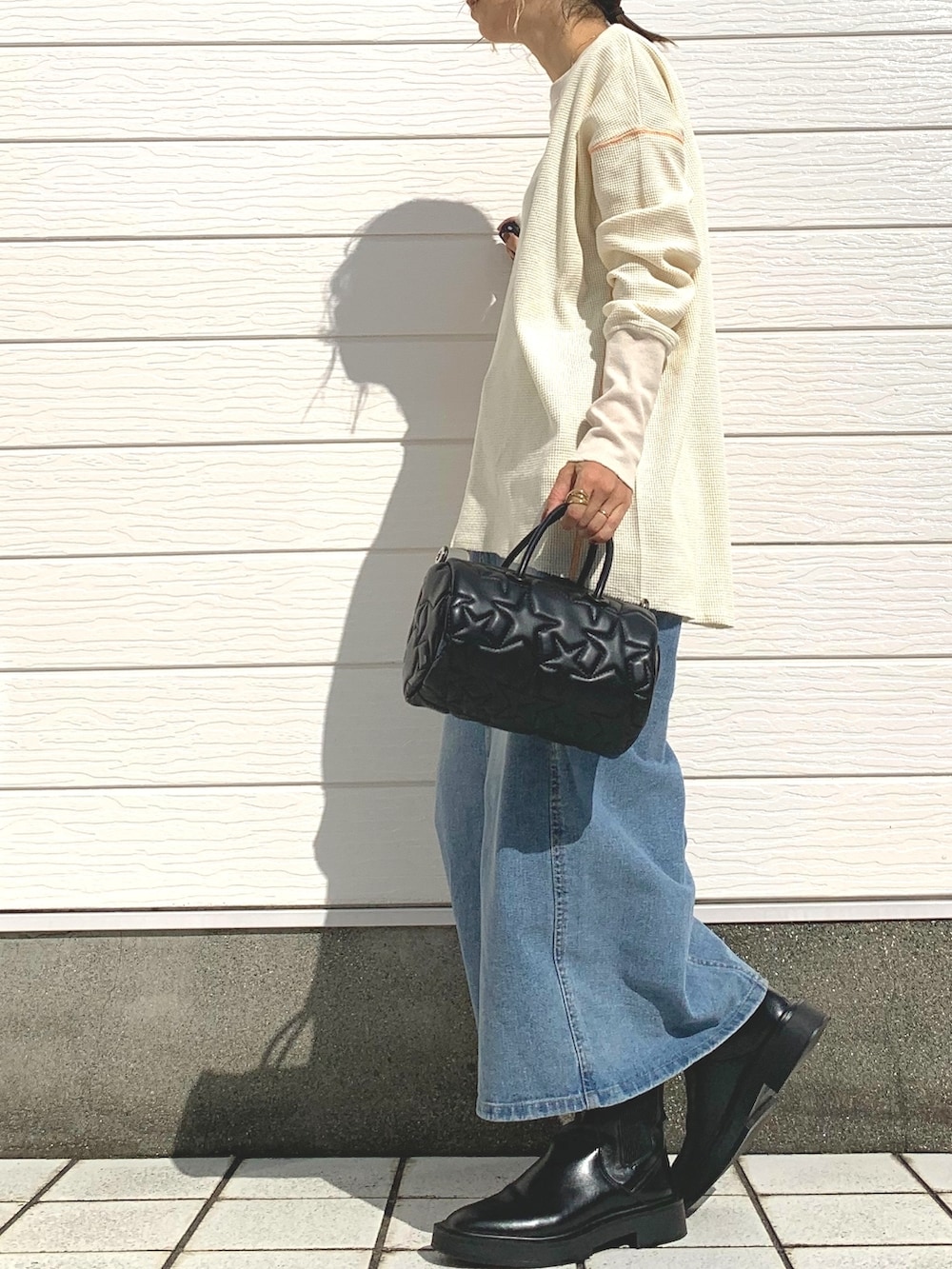 ブラック系のドラムバッグ、ブルー系のデニムスカート、ホワイト系のTシャツ/カットソーを着用したレディースの秋コーディネートの2枚目の写真