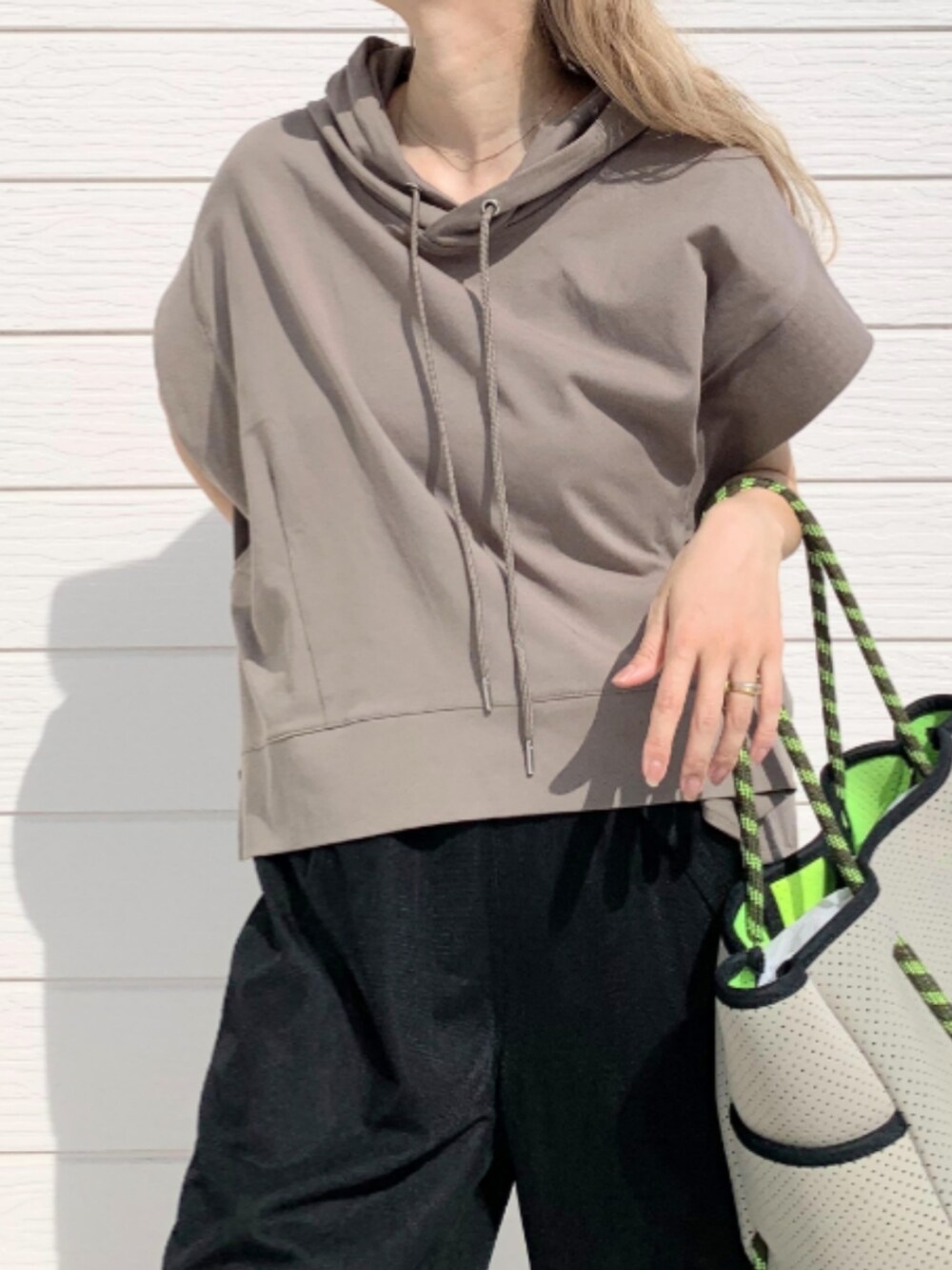 ブラック系のその他パンツ、グレー系のトートバッグ、グリーン系のパーカーを着用したレディースの春コーディネートの3枚目の写真