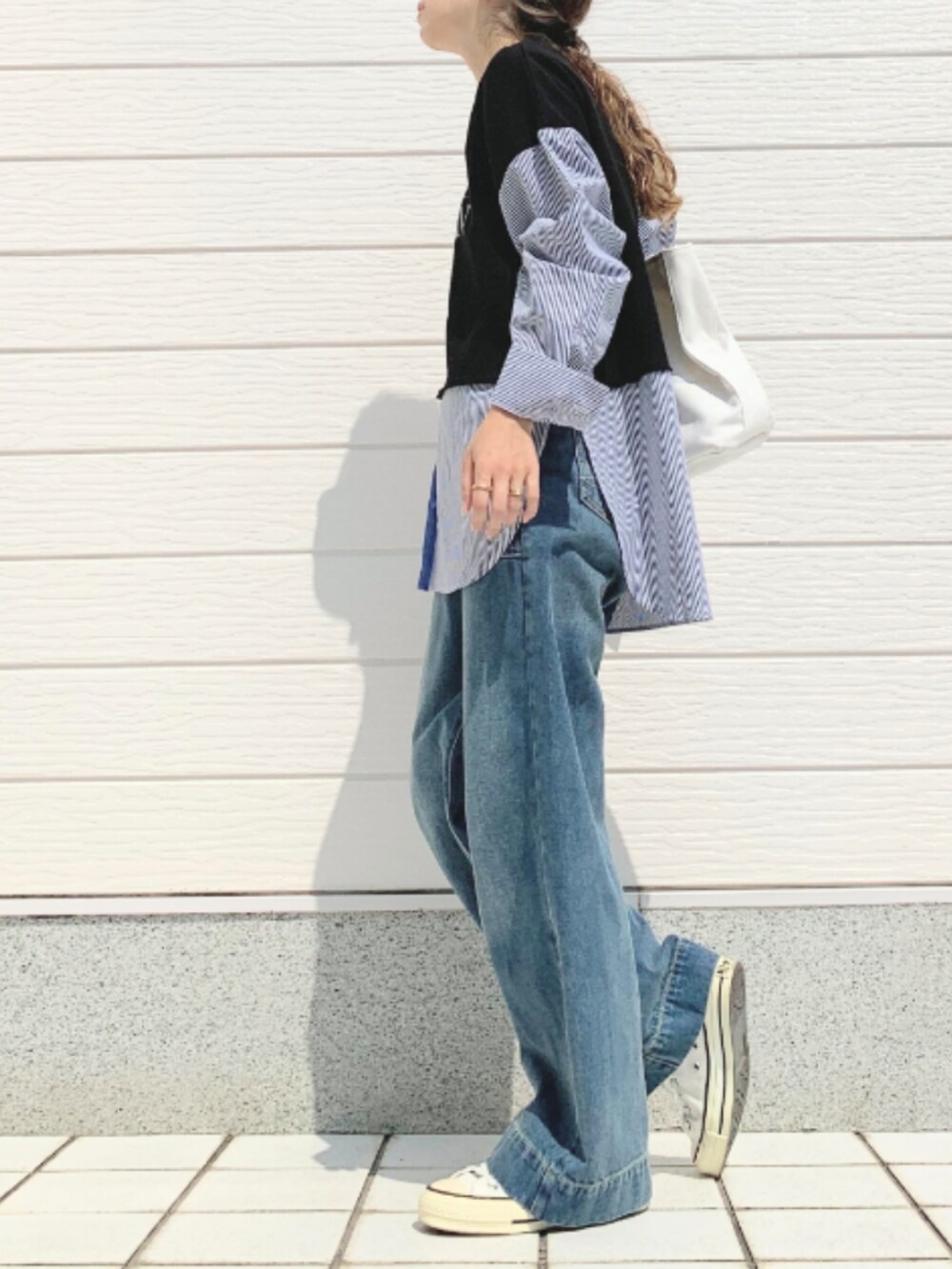 ホワイト系のトートバッグ、ブルー系のデニムパンツ、ホワイト系のスニーカーを着用したレディースの夏コーディネートの2枚目の写真