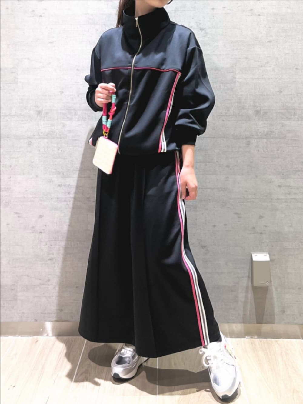 シルバー系のスニーカー、ブラック系のスカート、ブラック系のその他アウターを着用したレディースの春コーディネートの2枚目の写真