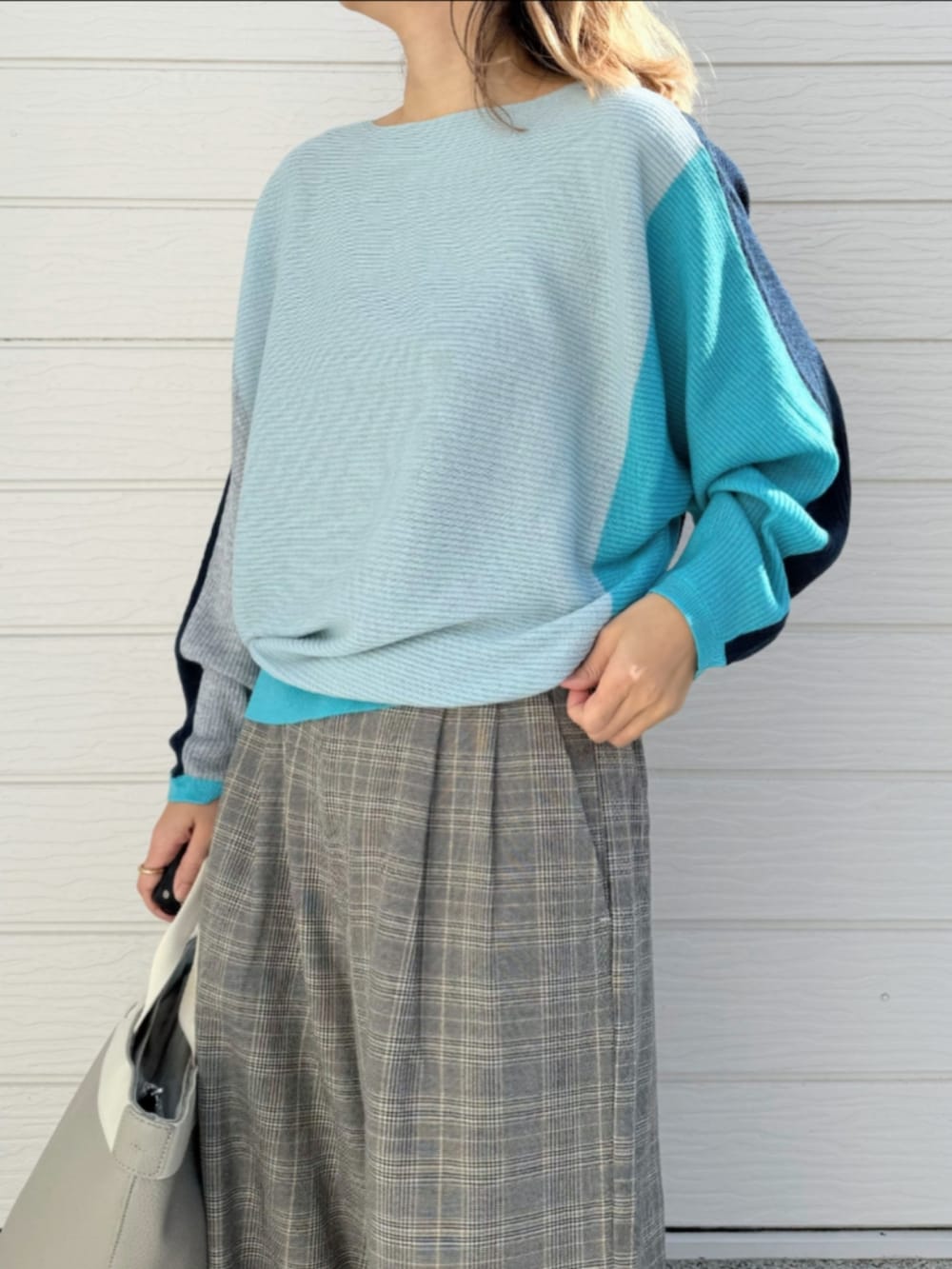 グレー系のトートバッグ、ブルー系のニット/セーター、ベージュ系のスラックスを着用したレディースの冬コーディネートの4枚目の写真