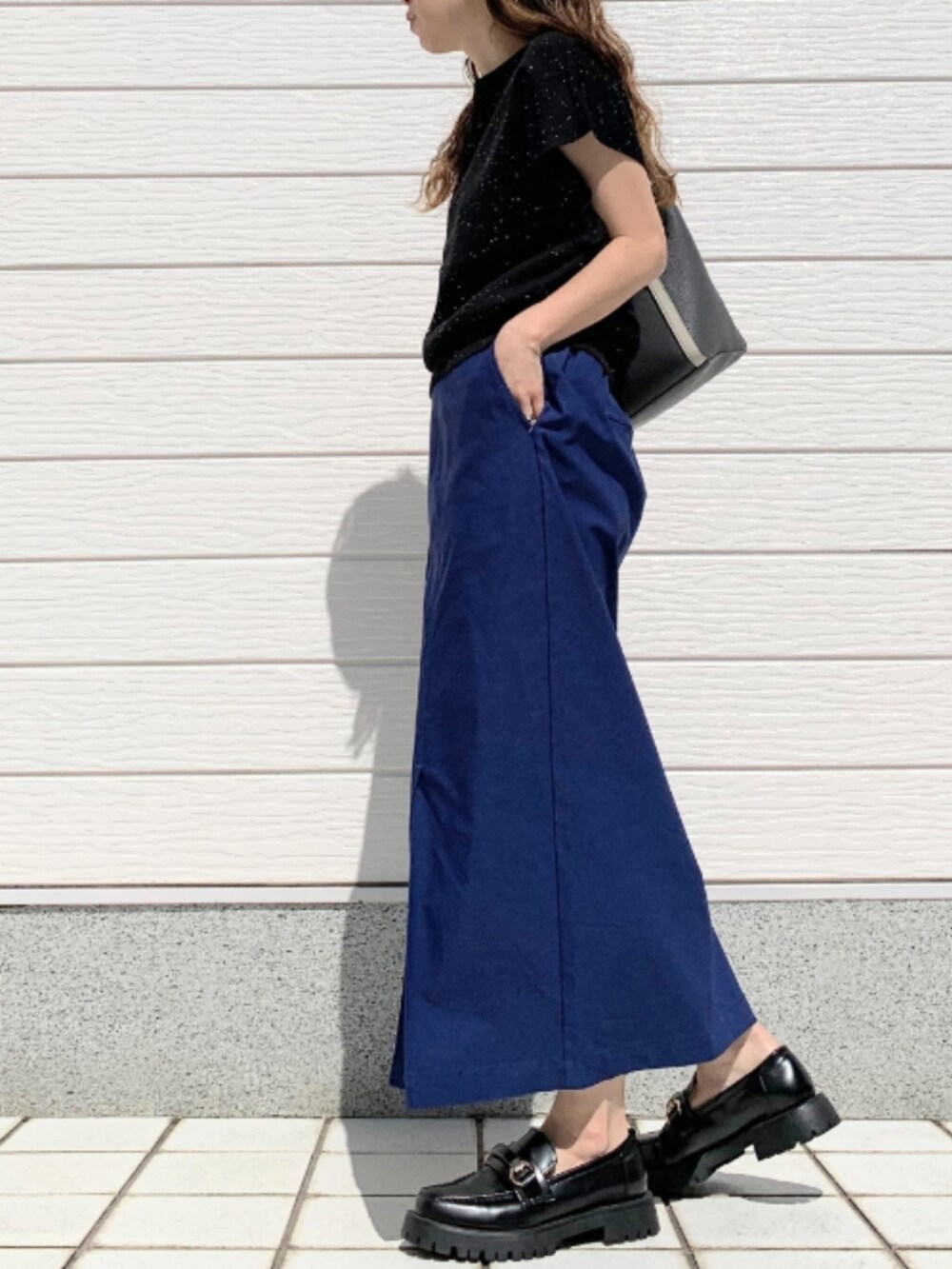 ブルー系のスカート、ブラック系のローファー、グレー系のトートバッグを着用したレディースの春コーディネートの2枚目の写真