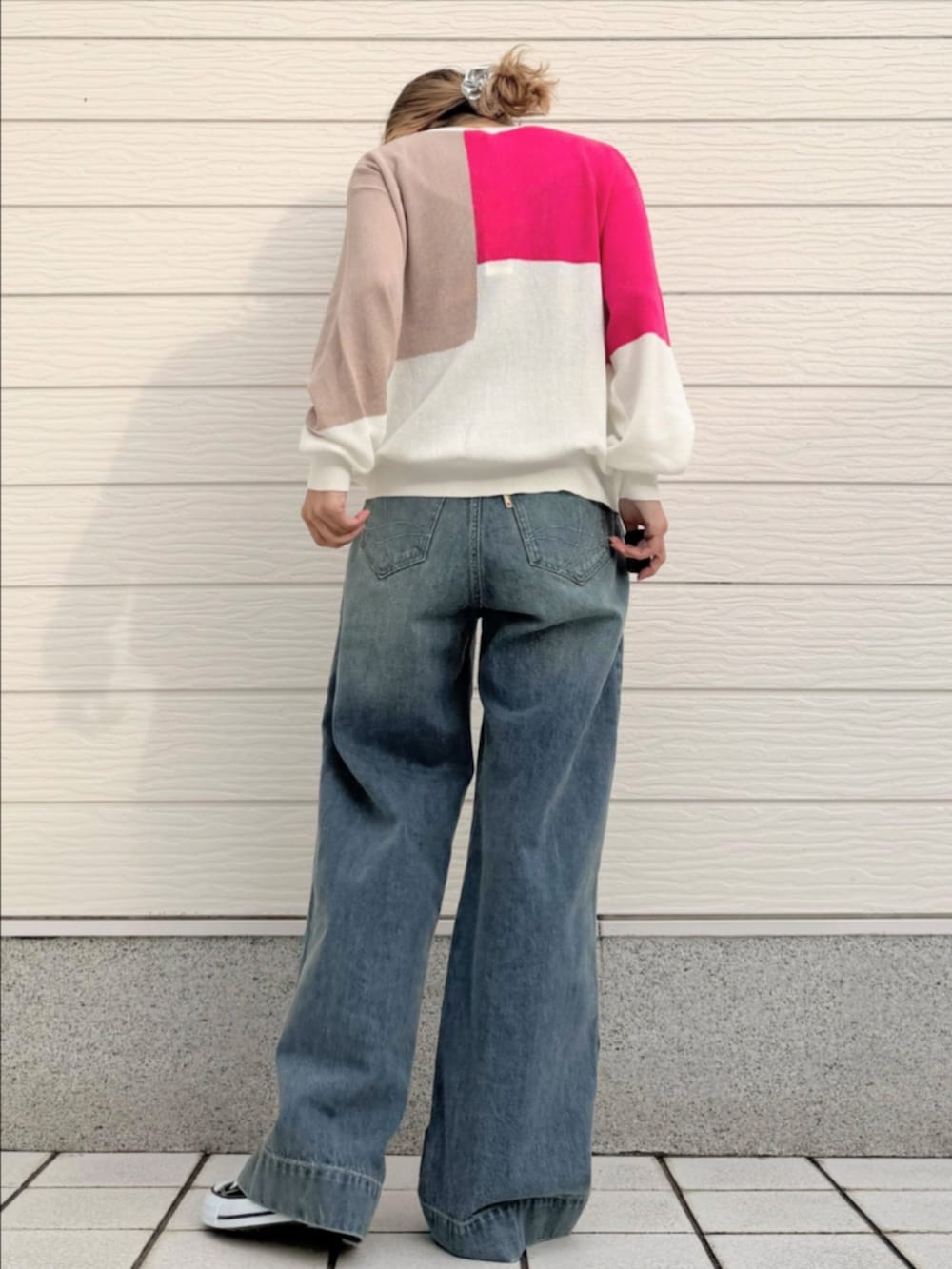 ブルー系のデニムパンツ、ホワイト系のニット/セーター、ブラック系のスニーカーを着用したレディースの冬コーディネートの3枚目の写真