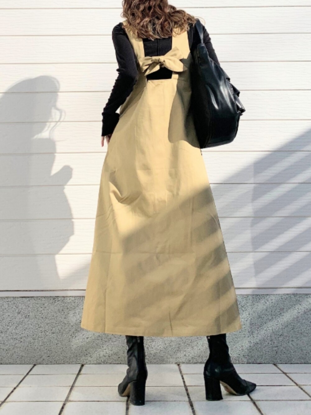 ベージュ系のジャンパースカート、ブラック系のトートバッグを着用したレディースの冬コーディネートの3枚目の写真