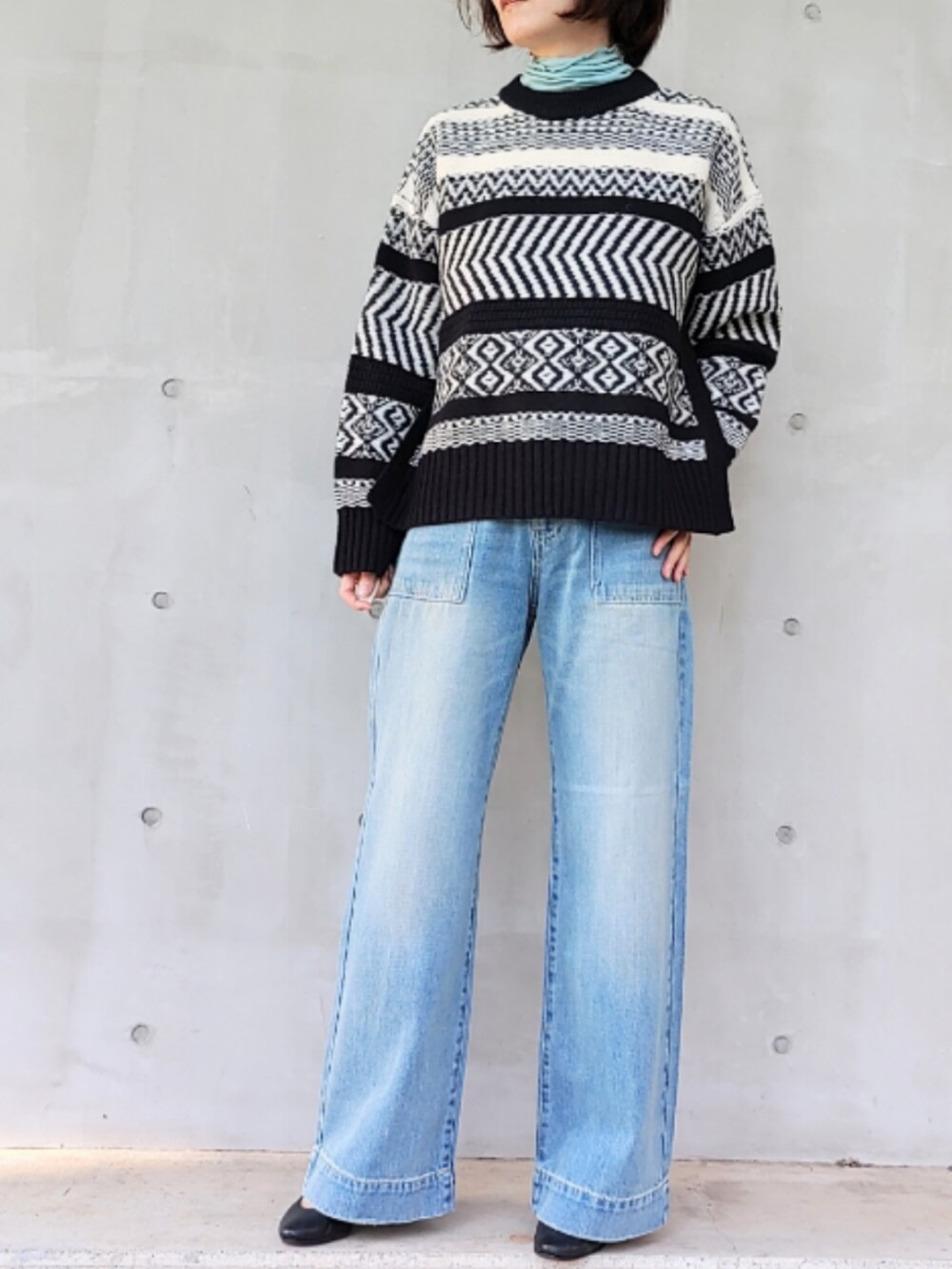 ブルー系のデニムパンツ、ブラック系のニット/セーター、ブルー系のTシャツ/カットソーを着用したレディースの秋コーディネートの2枚目の写真